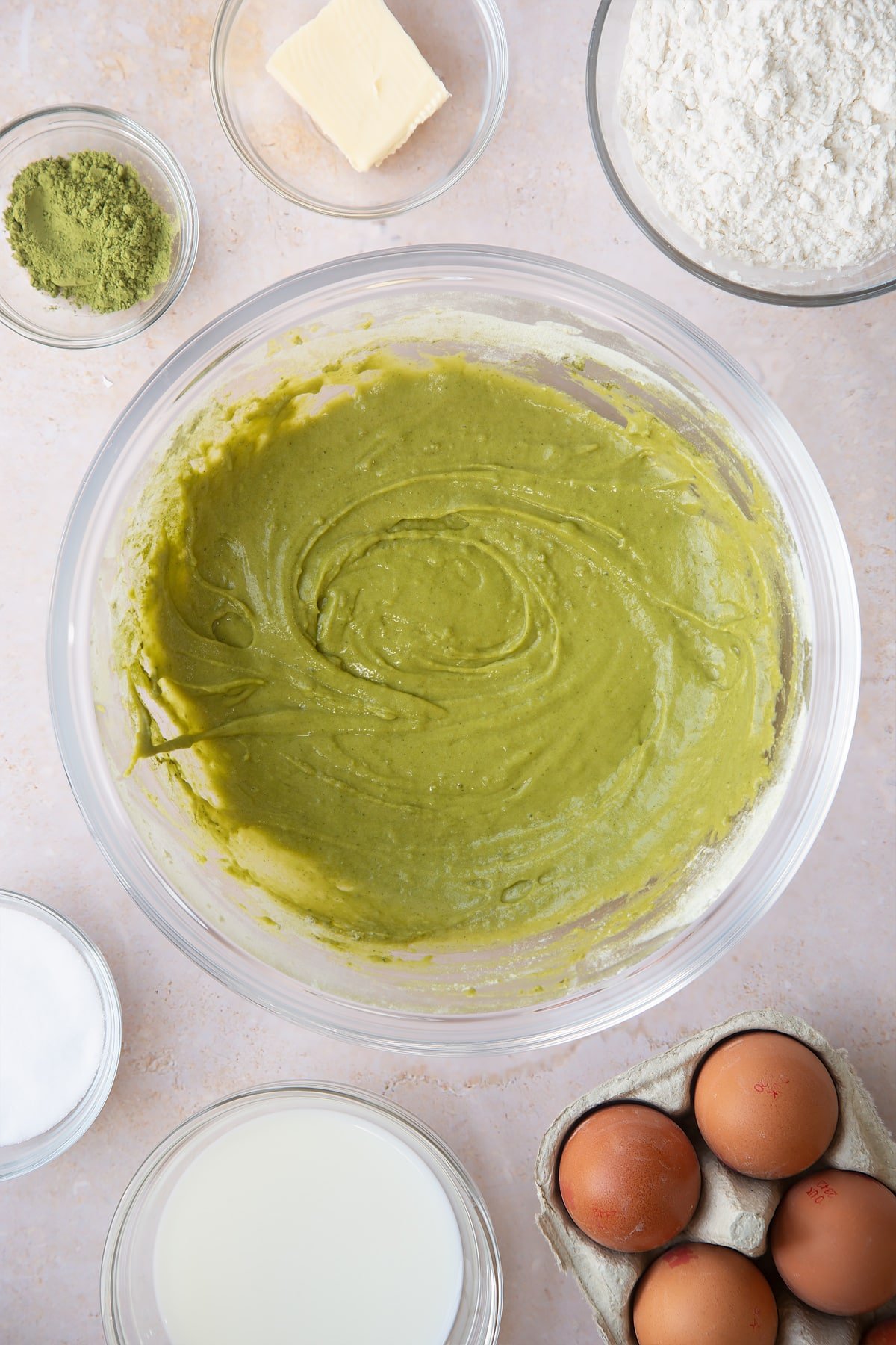 mixed matca pancake mix in a large clear bowl surrounded by ingredients.