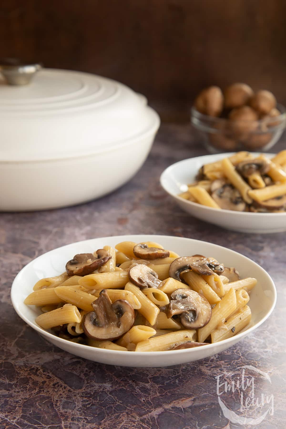 miso mushroom pasta in a white pasta bowl with a white casserole dish in the background.