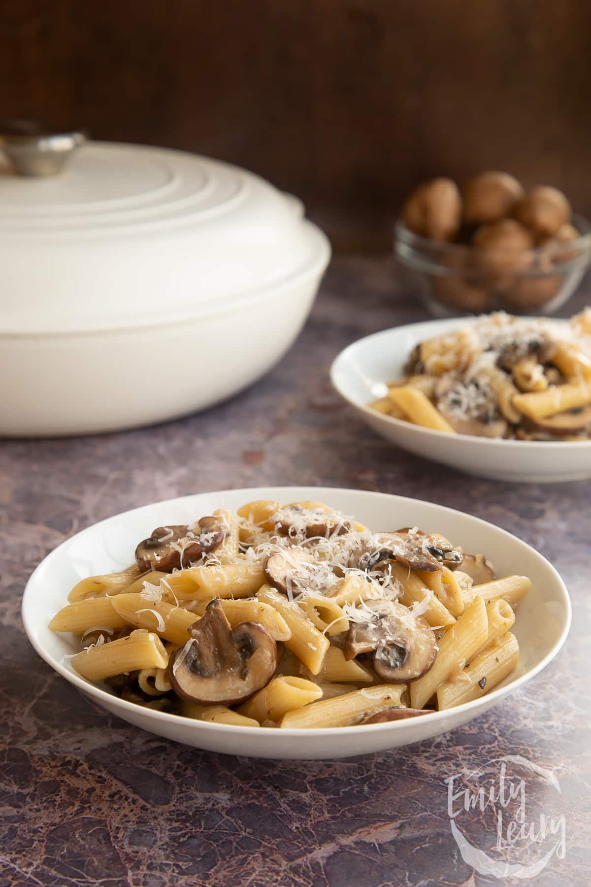 Miso mushroom pasta in a white pasta bowl topped with grated cheese.