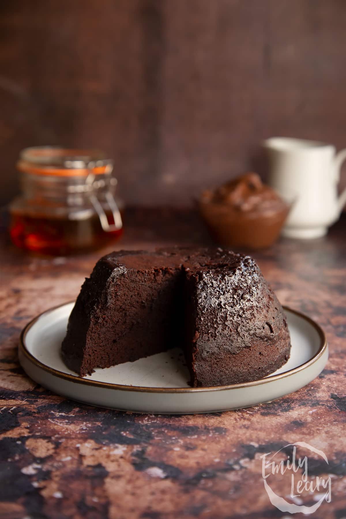 Nutella pudding cake with a slice cut out the front on a white plate.