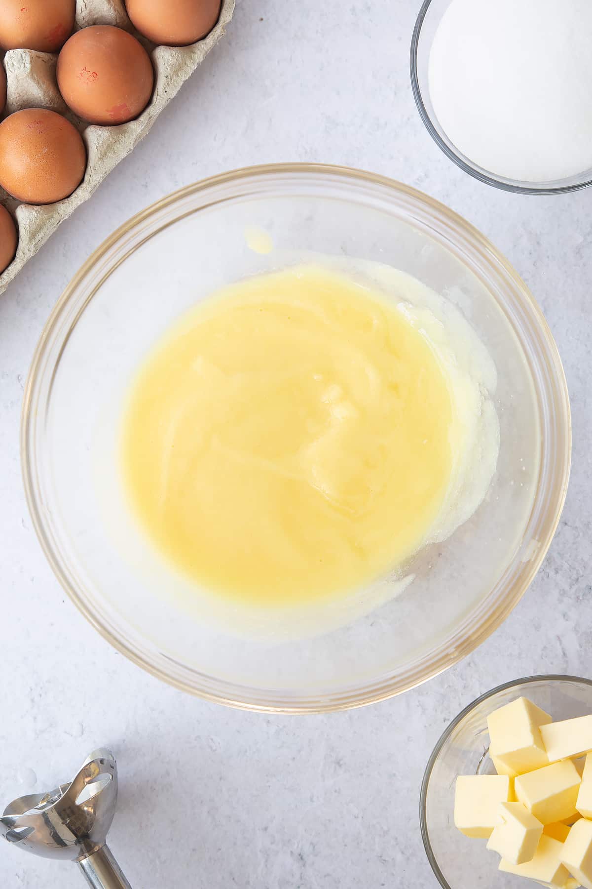 pineapple juice, butter and sugar in a large clear bowl surrounded by ingredients.