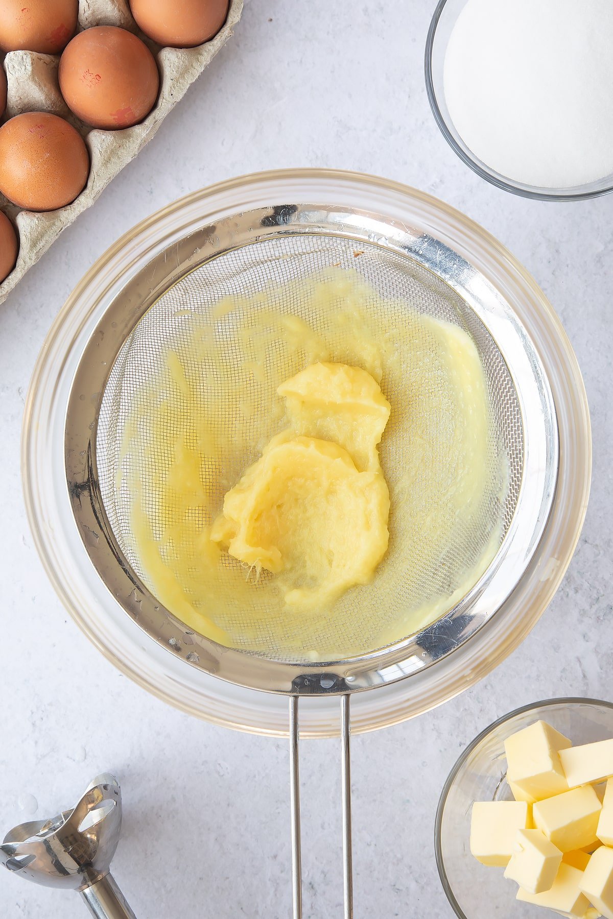 pineapple pulp in a sieve over a large clear bowl