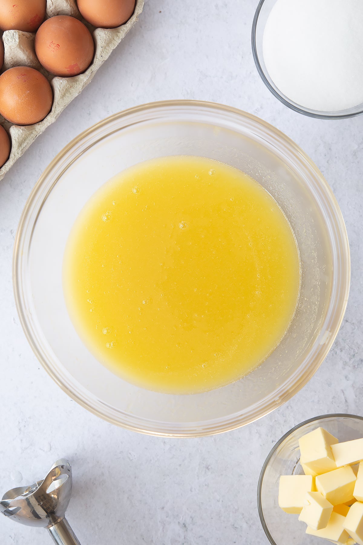 mixed pineapple juice, butter and sugar in a large clear bowl surrounded by ingredients.