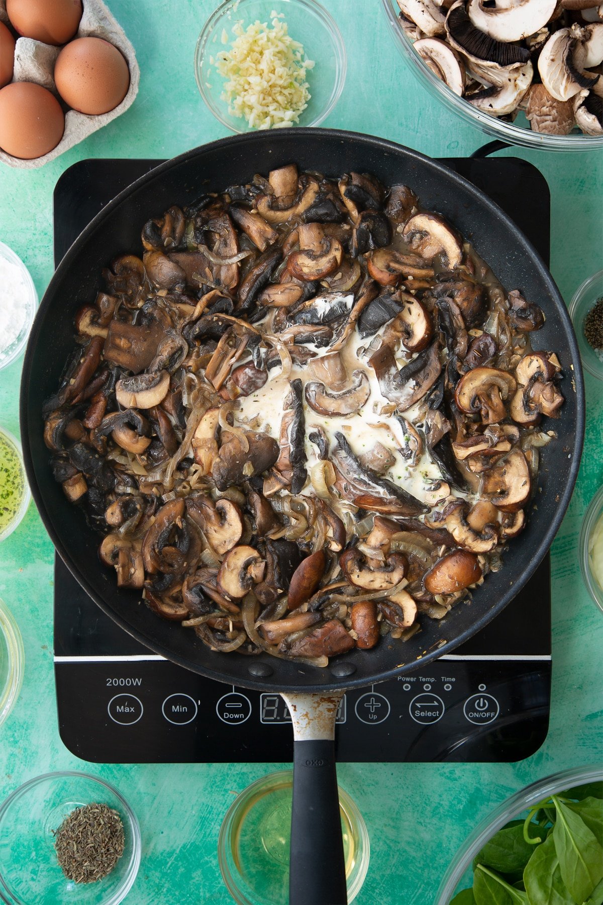 a large frying pan with cooked onions, herbs and garlic in a white wine sauce topped with sliced mushrooms and cornflour.