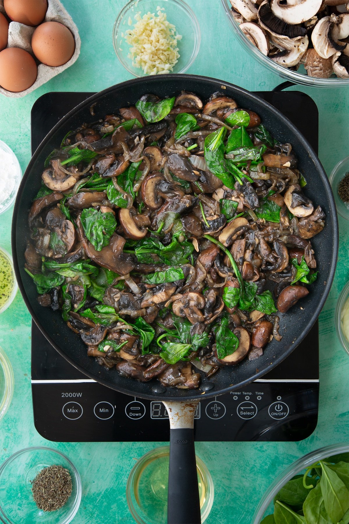 a large frying pan with cooked onions, mushrooms and spinach in a white wine sauce.