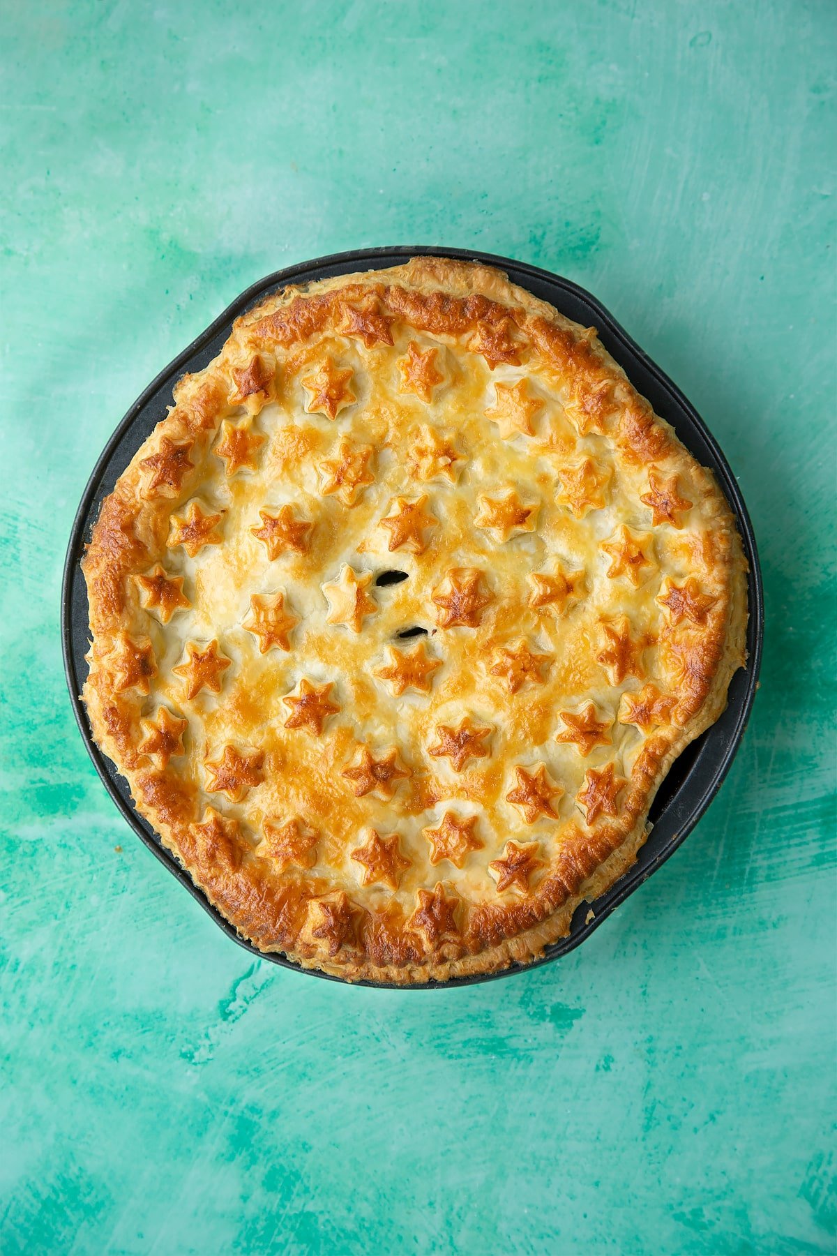 A cooked pie with stars on top in a black pie dish.