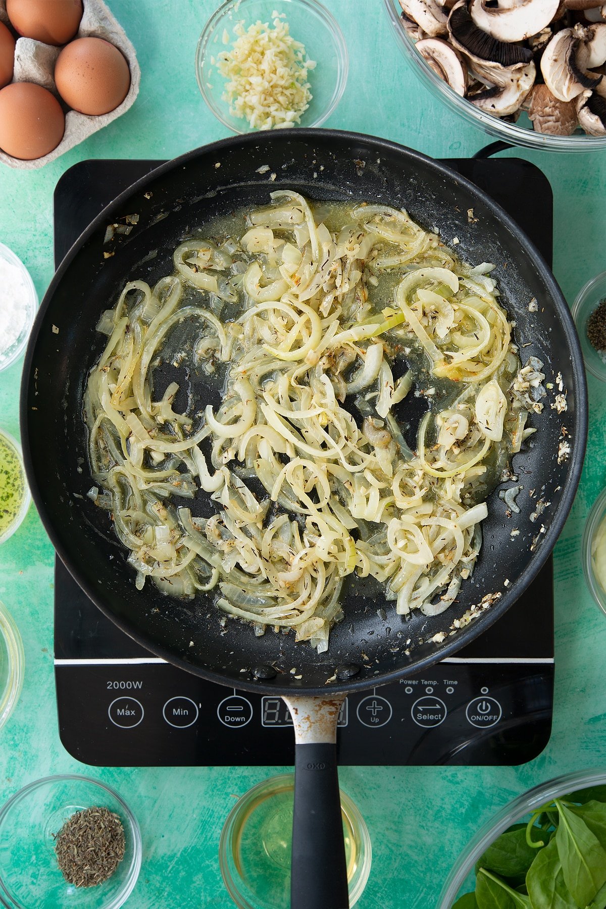 a large frying pan with cooked onions, herbs and garlic in a butter sauce.