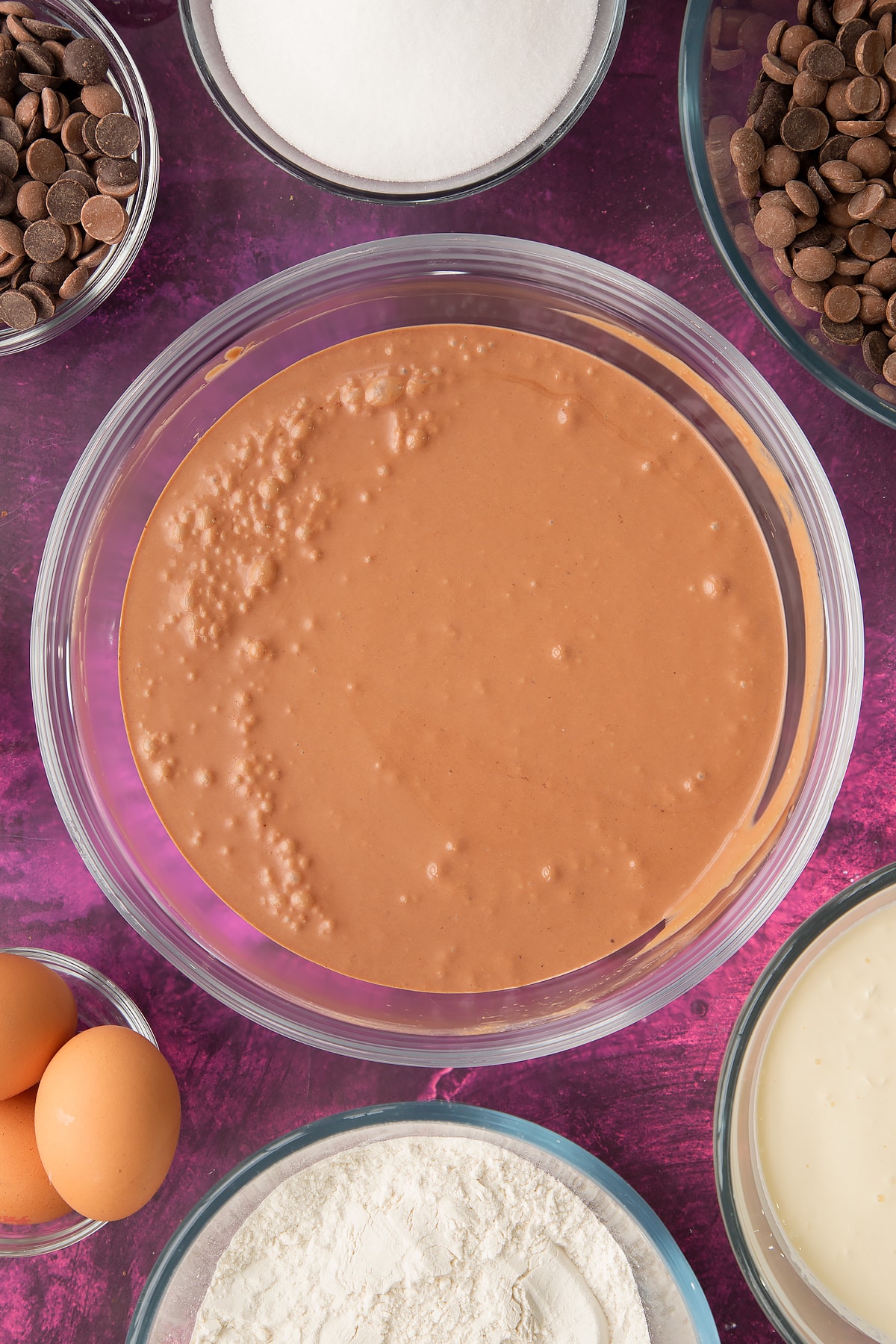 whisked chocolate cake batter in a large clear bowl.