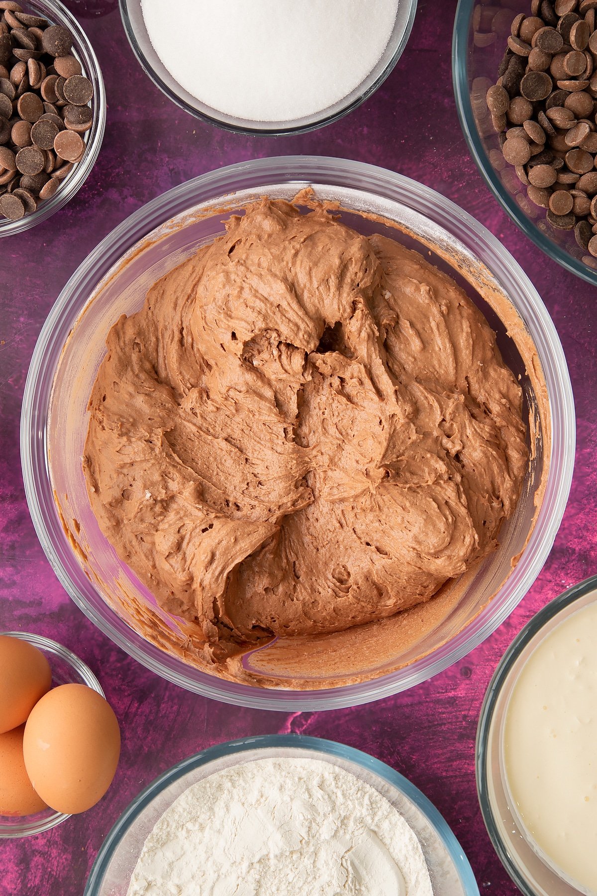 chocolate vanilla cake batter mixed with flour and bicarbonate soda in a large clear bowl.