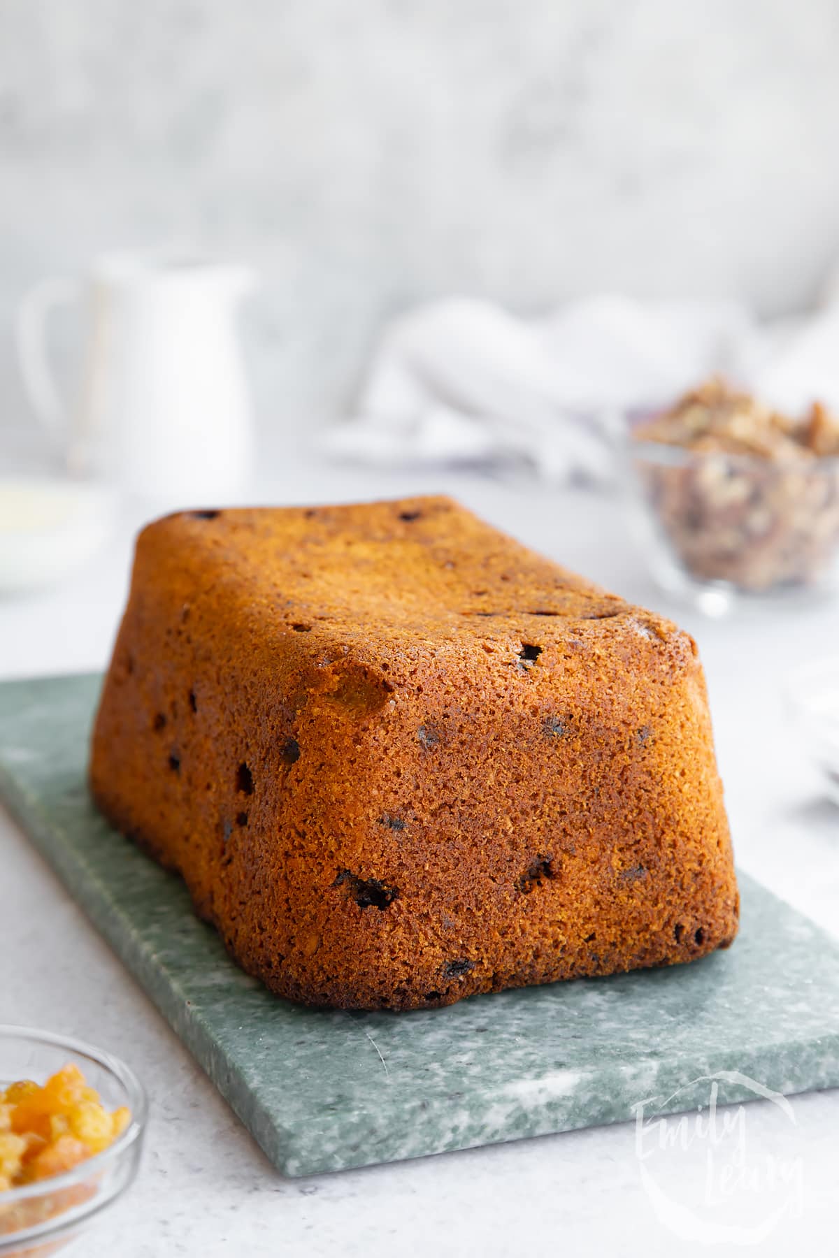 baked vegan carrot cake loaf on a green marble chopping board.