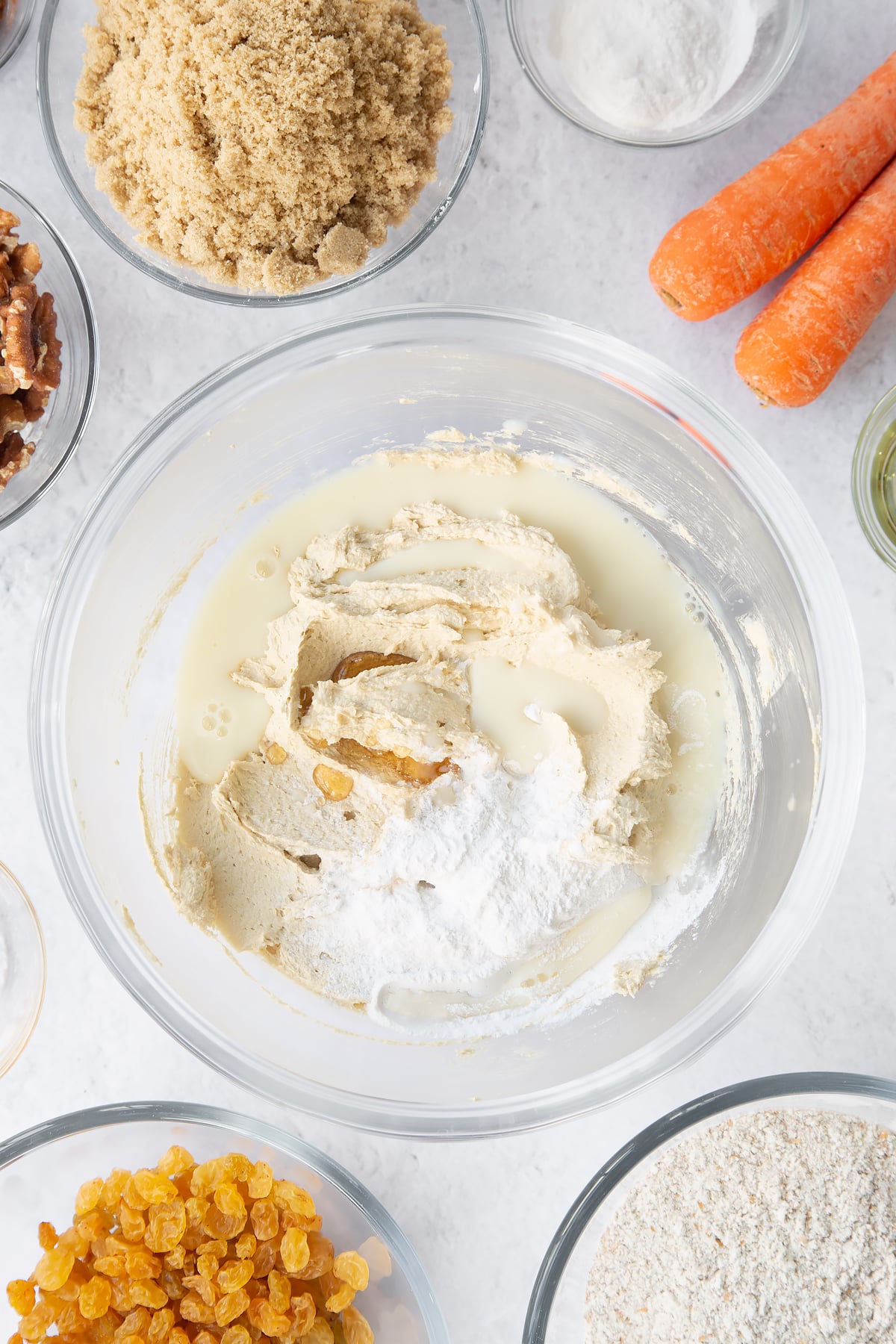 whisked vegan butter, oil and sugar in a large clear bowl topped with egg replacement powder, vanilla and plant milk.