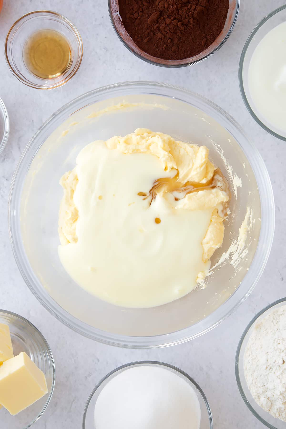 whisked butter, egg and sugar mix in a large clear bowl topped with buttermilk and vanilla.