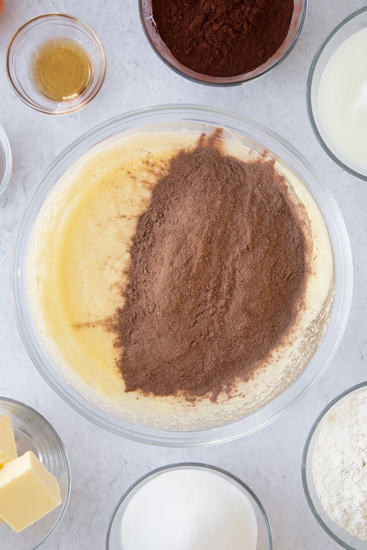 whisked buttermilk and sugar mix in a large clear bowl to create a batter topped with cocoa flour mix.