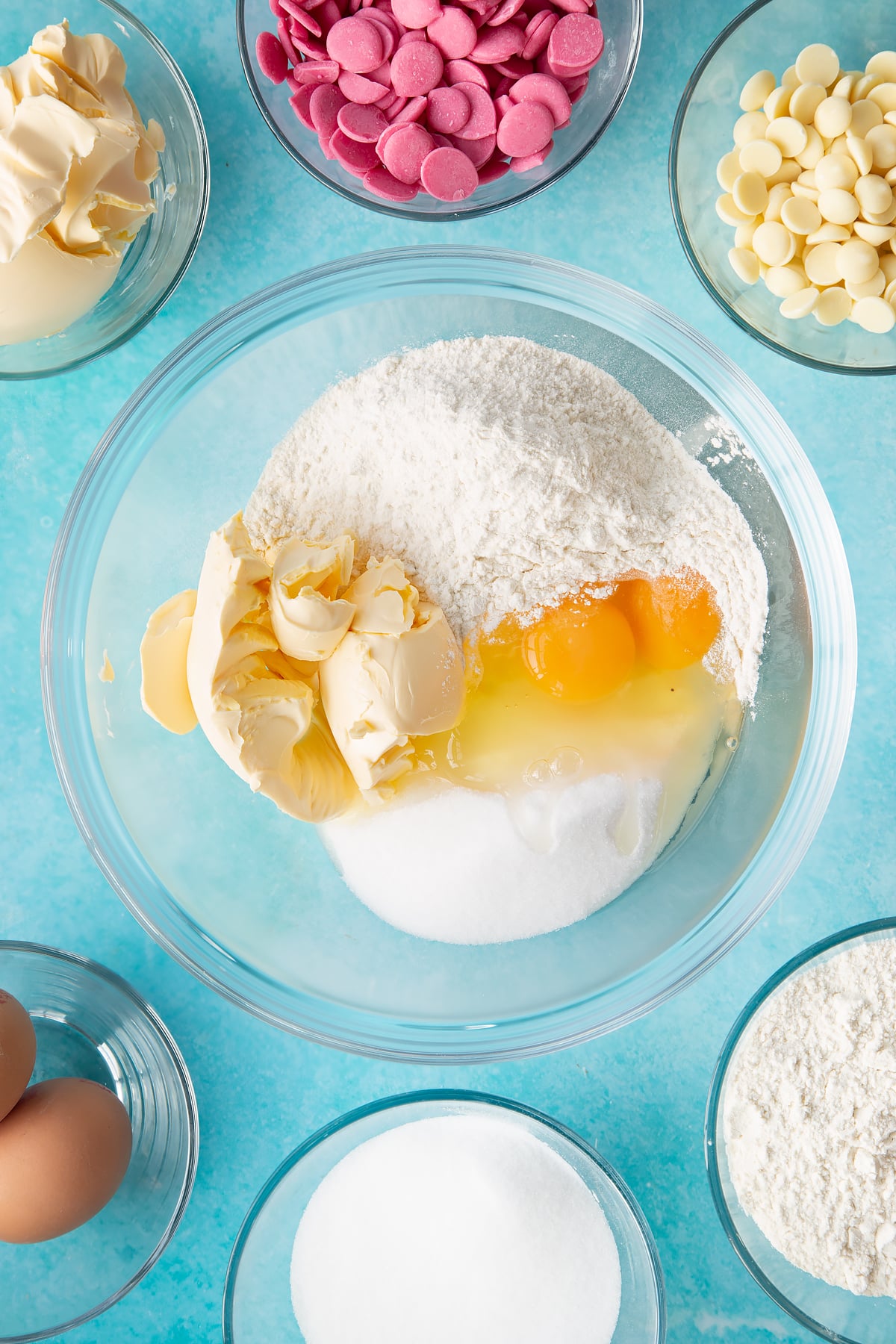 margarine, sugar, eggs and flour in a large clear bowl surrounded bu ingredients.