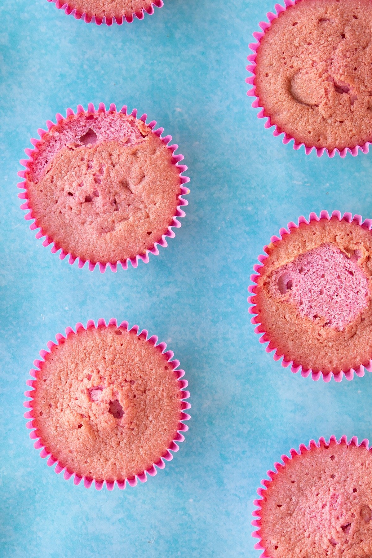 Pink cupcakes in pink cupcake liners on a blue background.