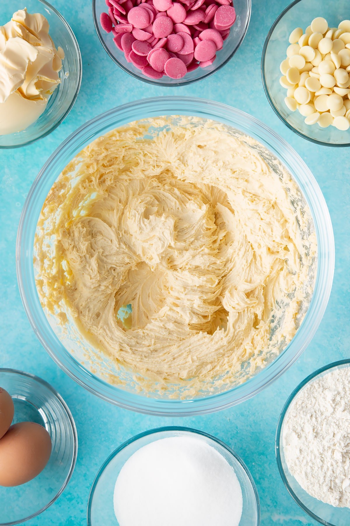 whisked margarine, sugar, eggs and flour in a large clear bowl surrounded by ingredients.