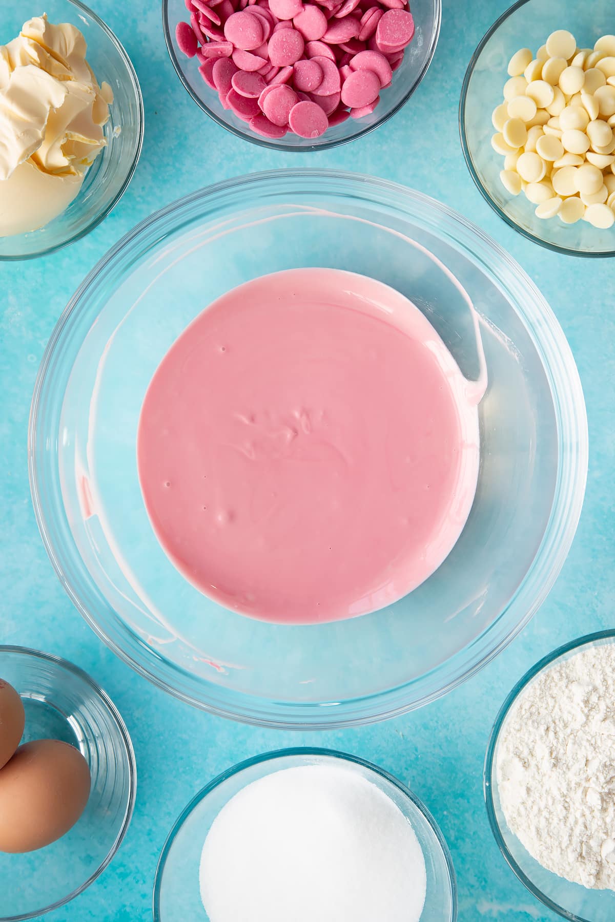melted pink candy melts and white chocolate mixed together in a large clear bowl.