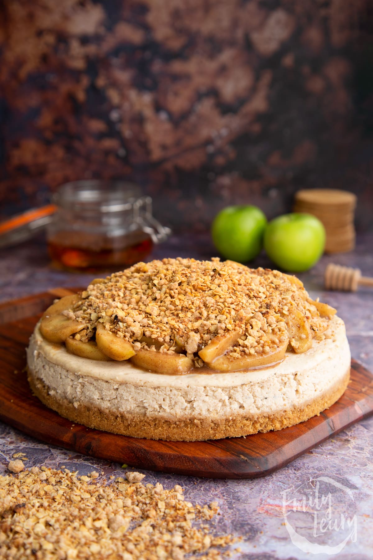 The finished apple crumble cheesecake on a wooden board.