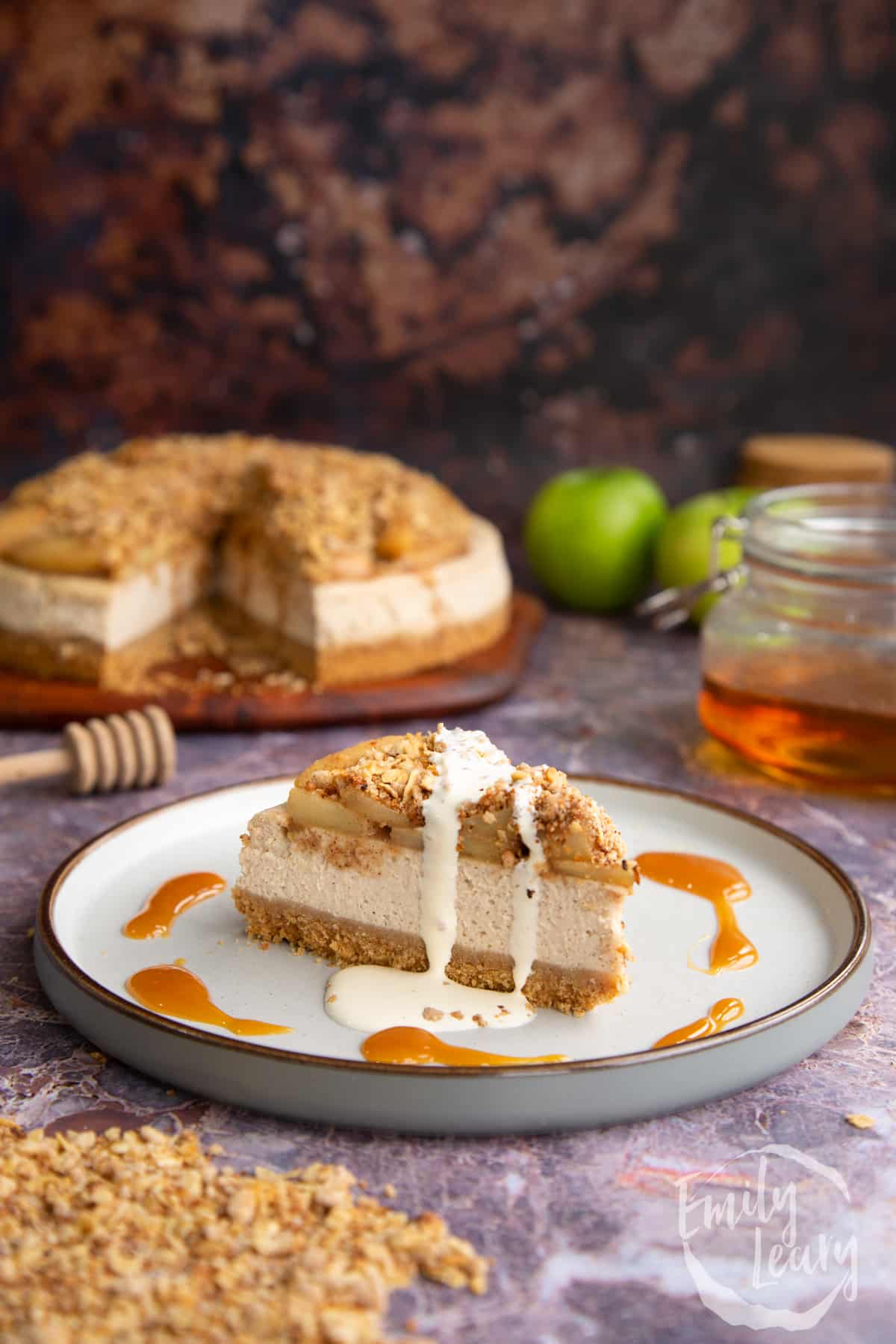 A finished slice of apple crumble cheesecake served on a decorative white plate.