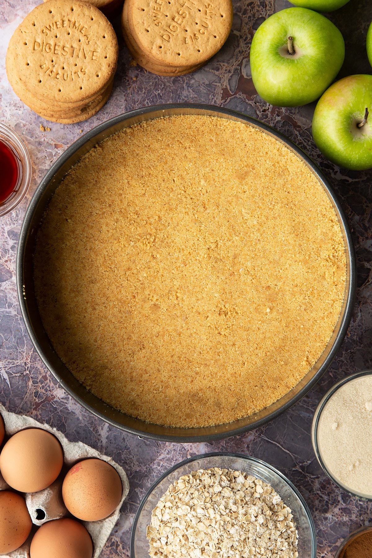 Overhead shot of the baking tin having compressed the base of the cheesecake evenly. 