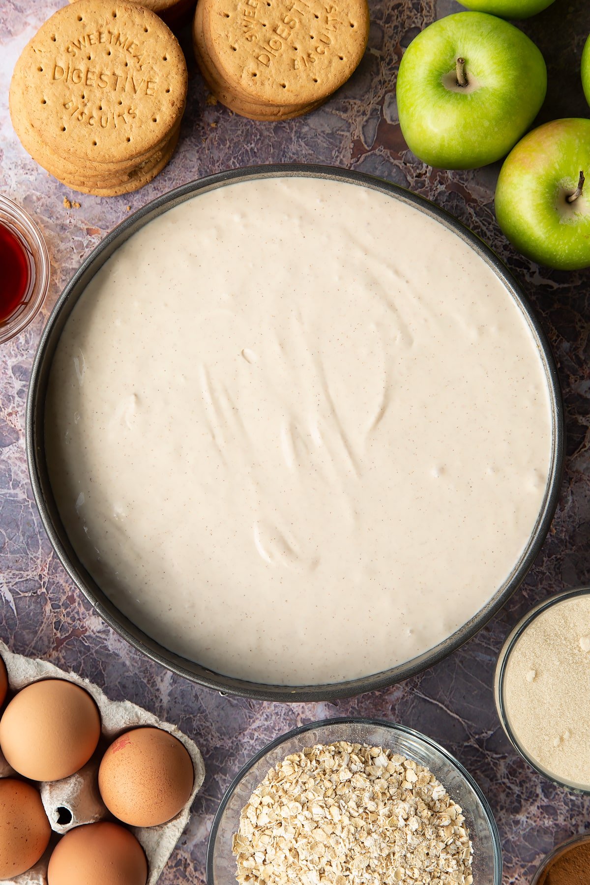 Adding the mixture to the top of the base for the cheesecake inside the baking tin. 