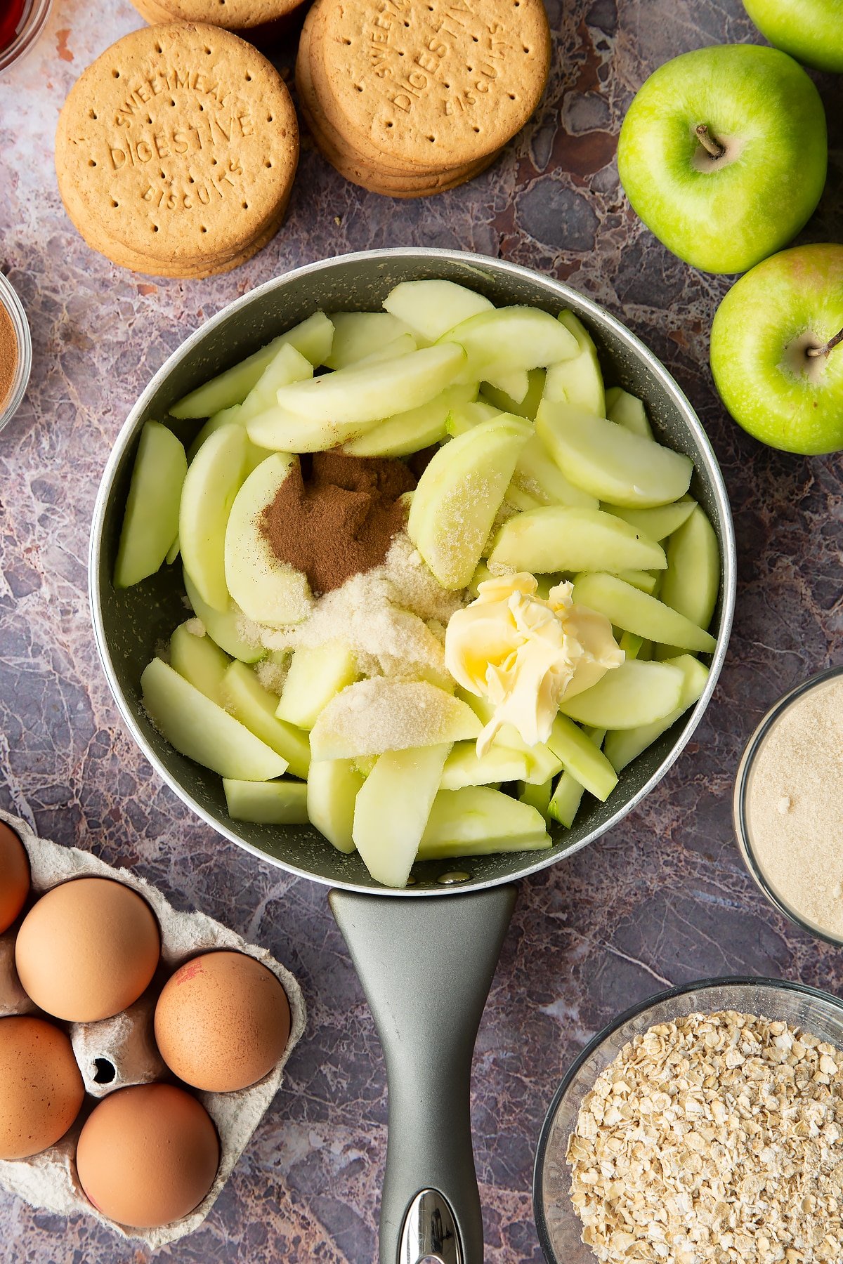 Adding apples together with butter, cinnamon and sugar into a large pan. 