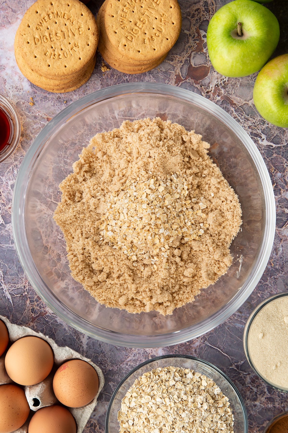 Adding the oats to the crumble mixture inside the mixing bowl.