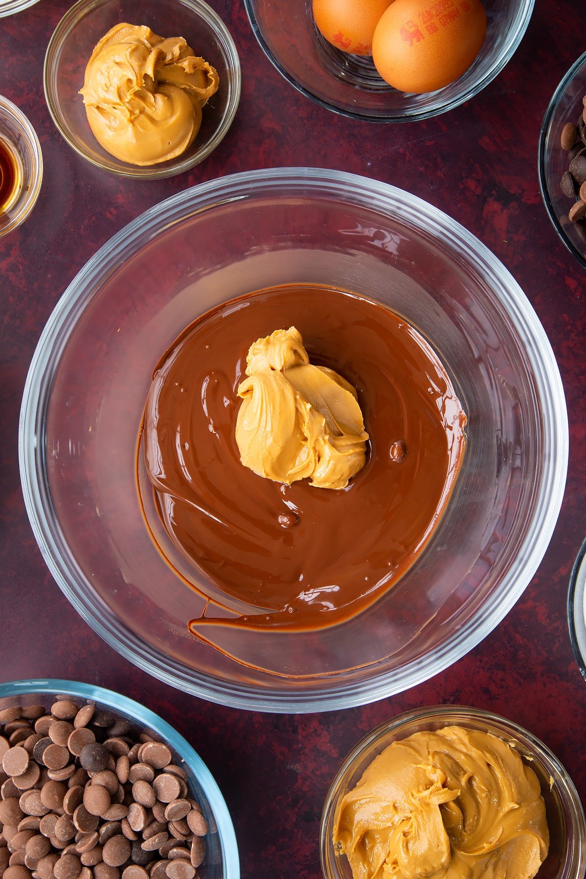 melted milk and dark chocolate chips in a large clear bowl topped with peanut butter.