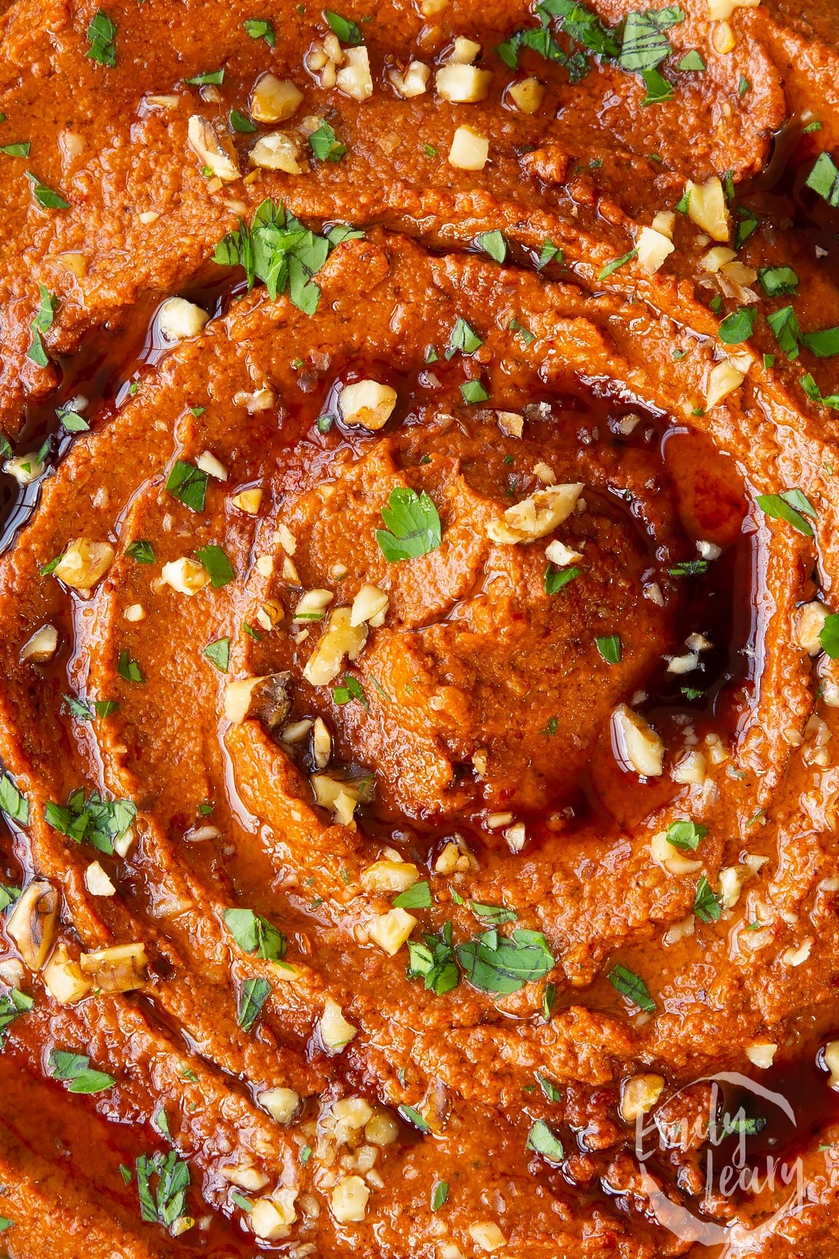 a close up shot of Red pepper dip topped with toasted walnuts.