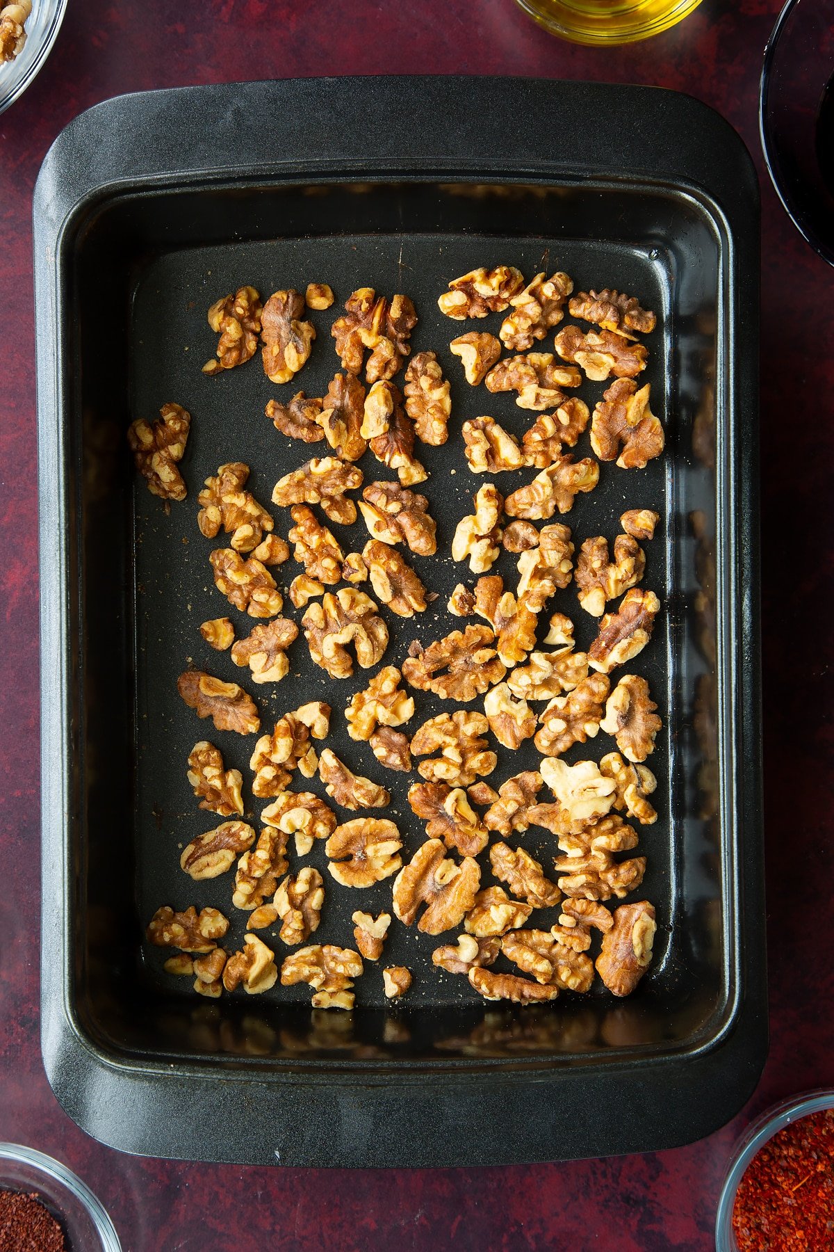 whole toasted walnuts spread into an even layer in the base of a baking tray.