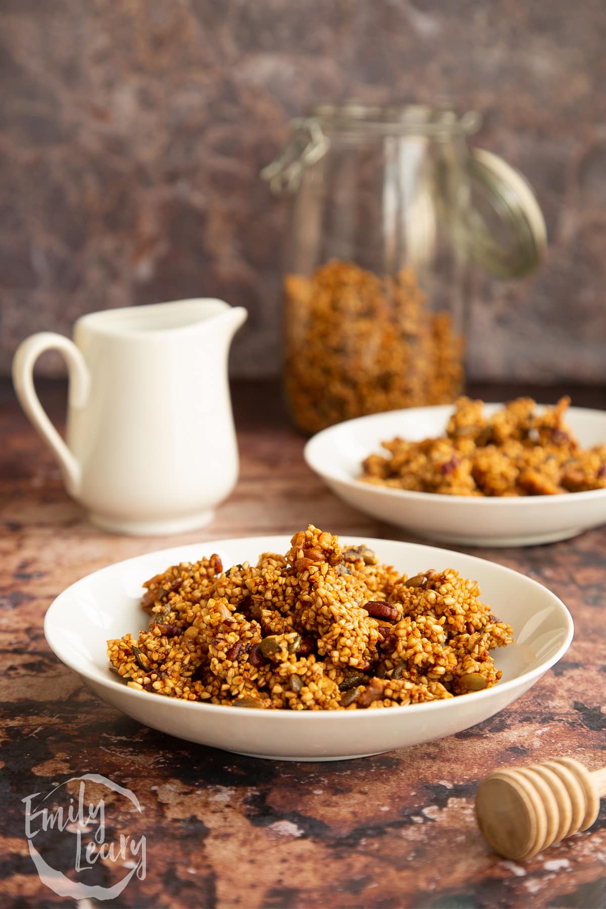 Steel cut oats granola in a white bowl next to a white milk jug.