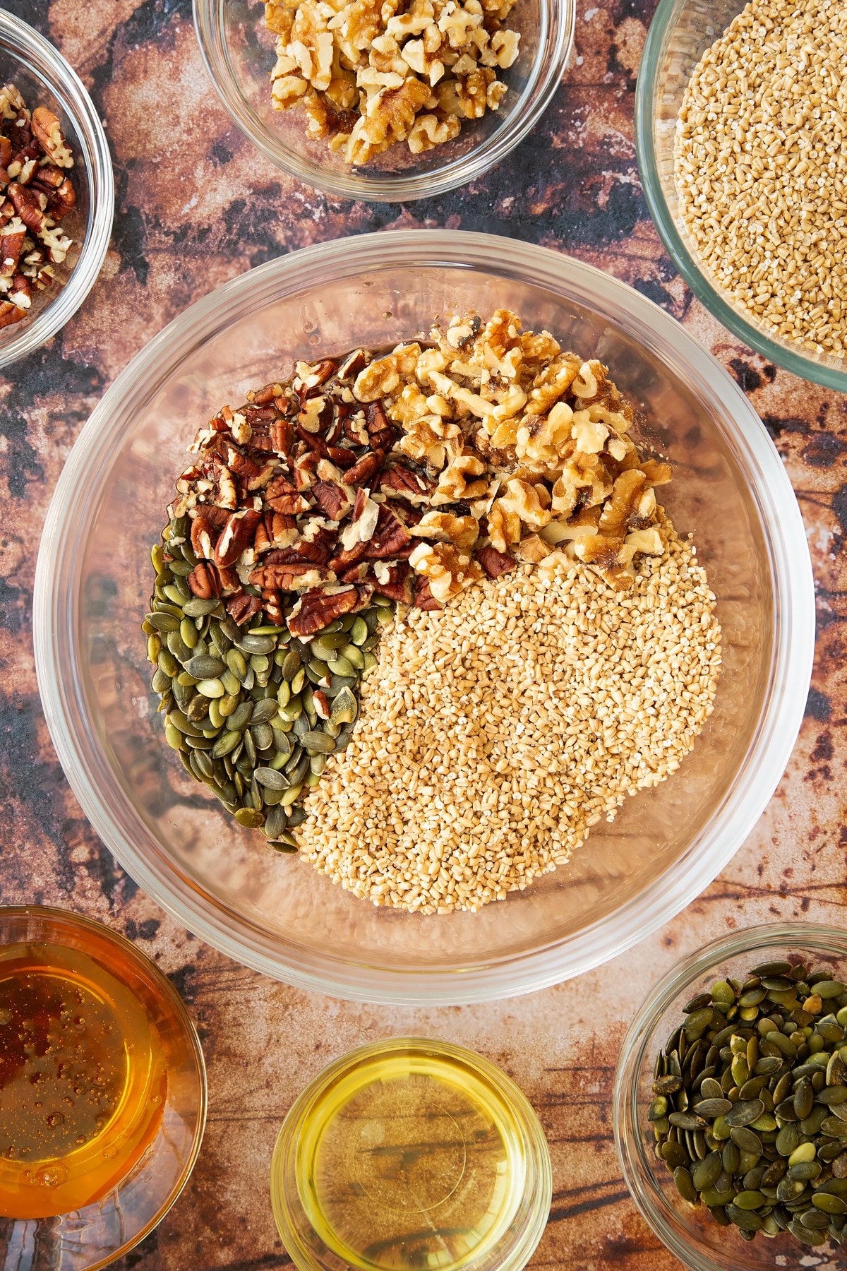 steel cut oats, pumpkin seeds, pecans and walnuts in a large clear bowl.