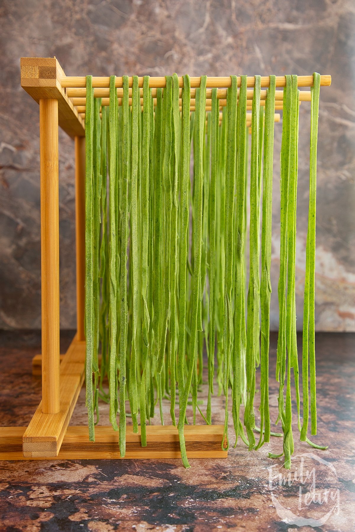 green Tagliatelle hung from a wooden pasta rack