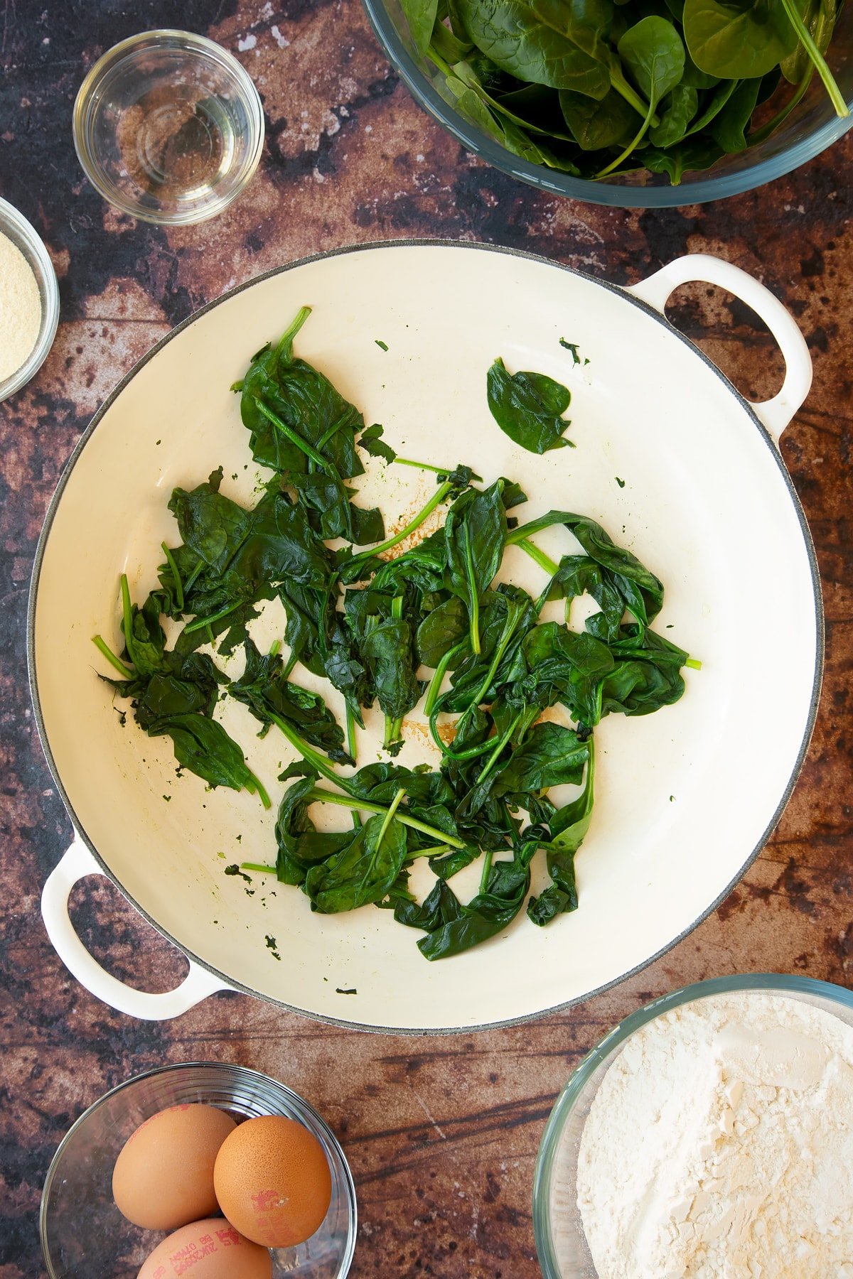 a large white pan with wilted spinach in the bottom.
