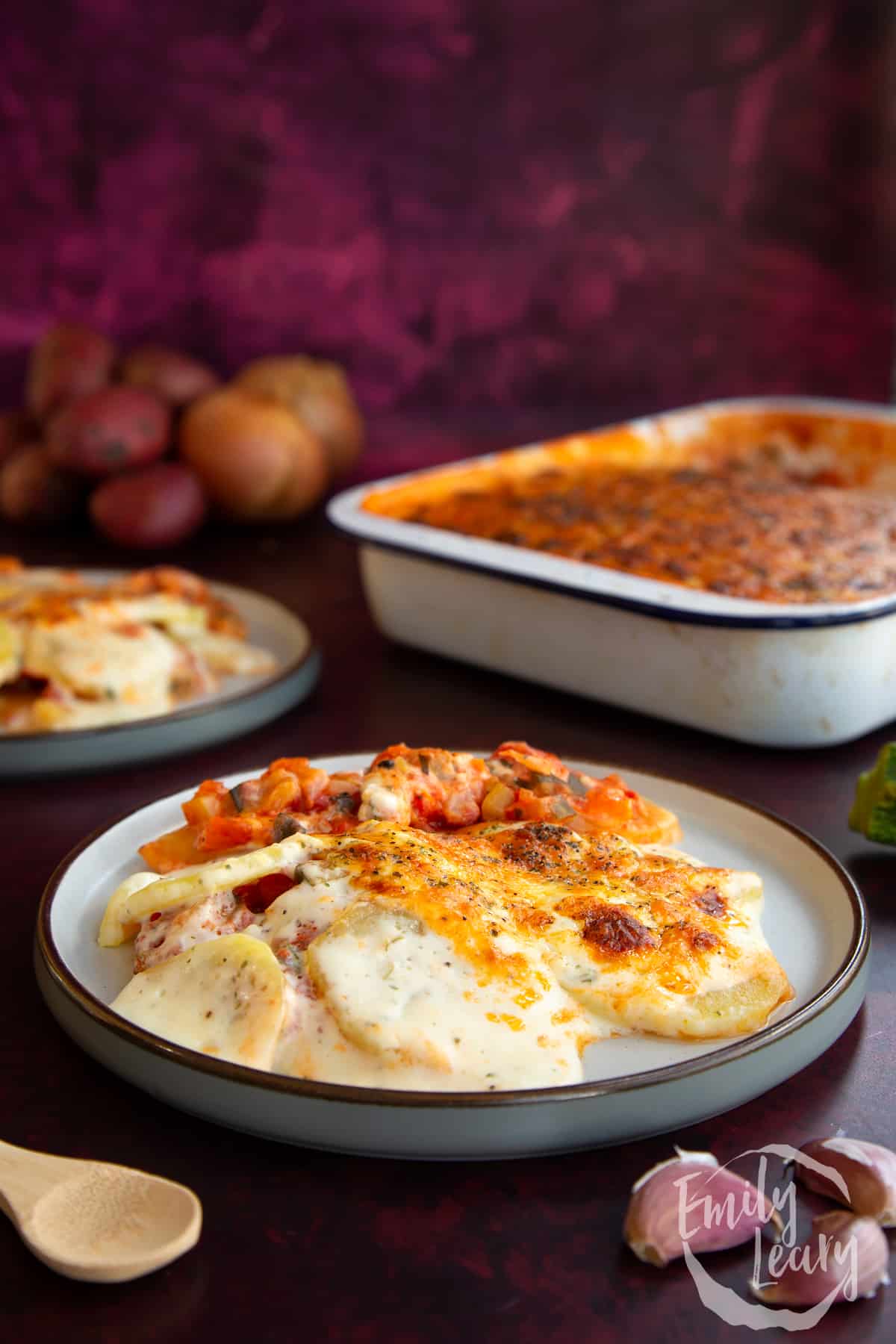 Side on shot of a plate of vegetarian potato lasagne with an additional plate in the background.