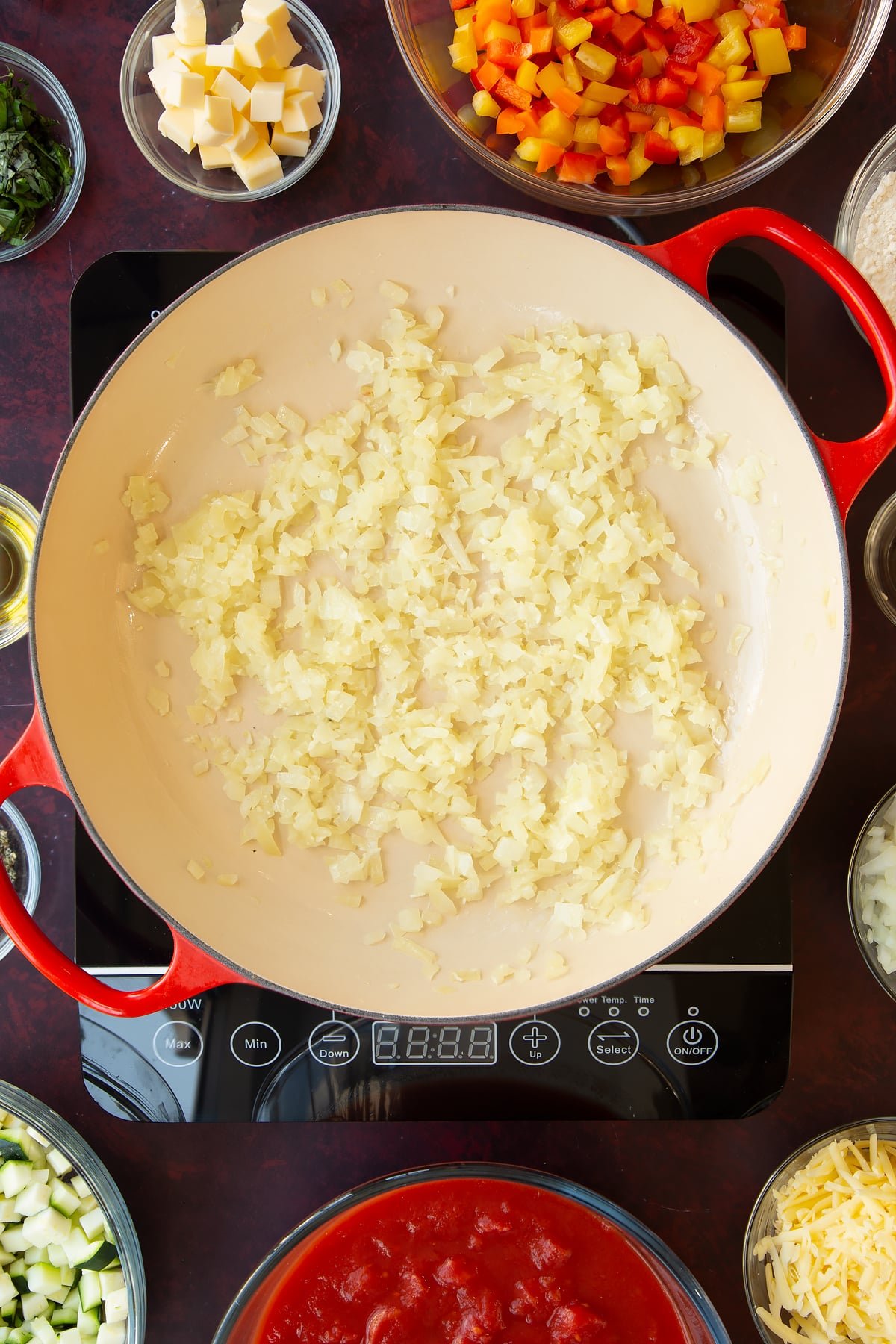 Overhead shot of some diced simmered onions in a red pan.