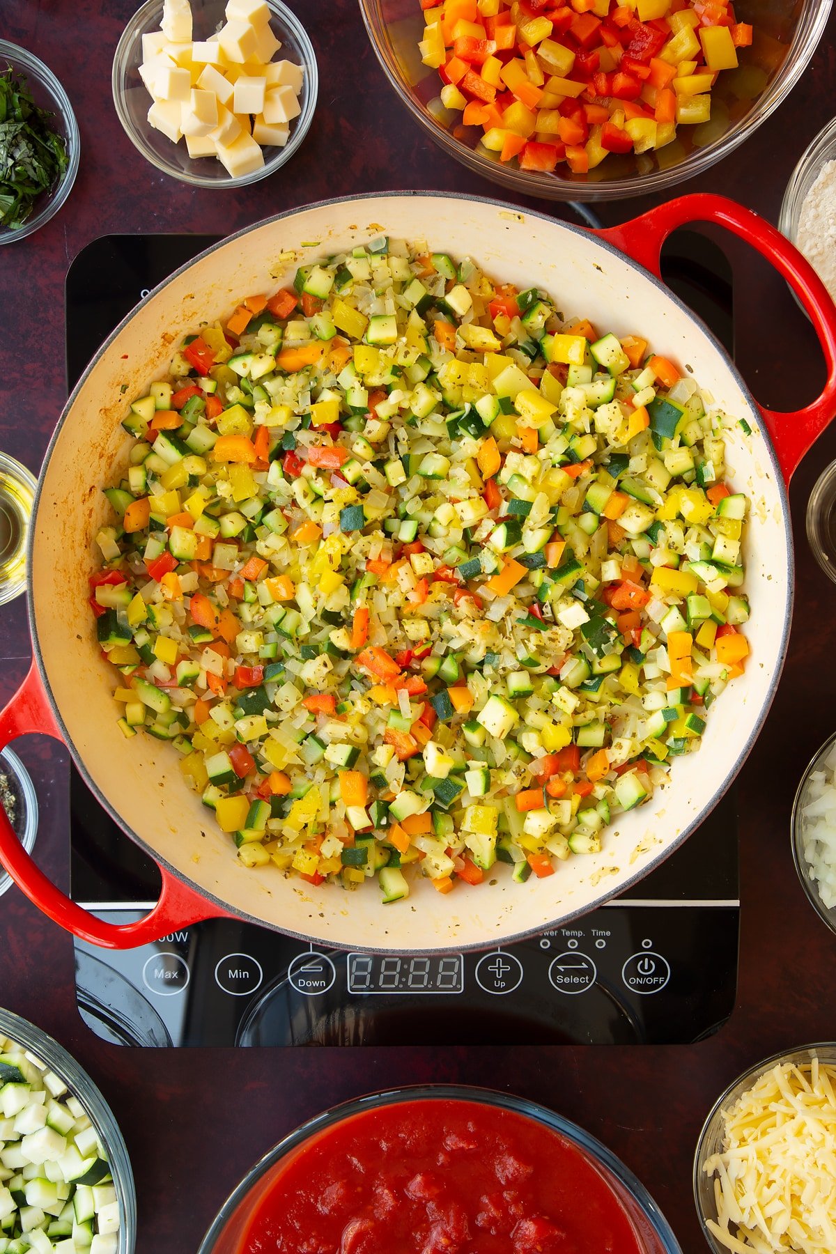 Overhead shot of finely sliced courgettes, peppers, sage, onion, salt and pepper having been fried for five minutes.