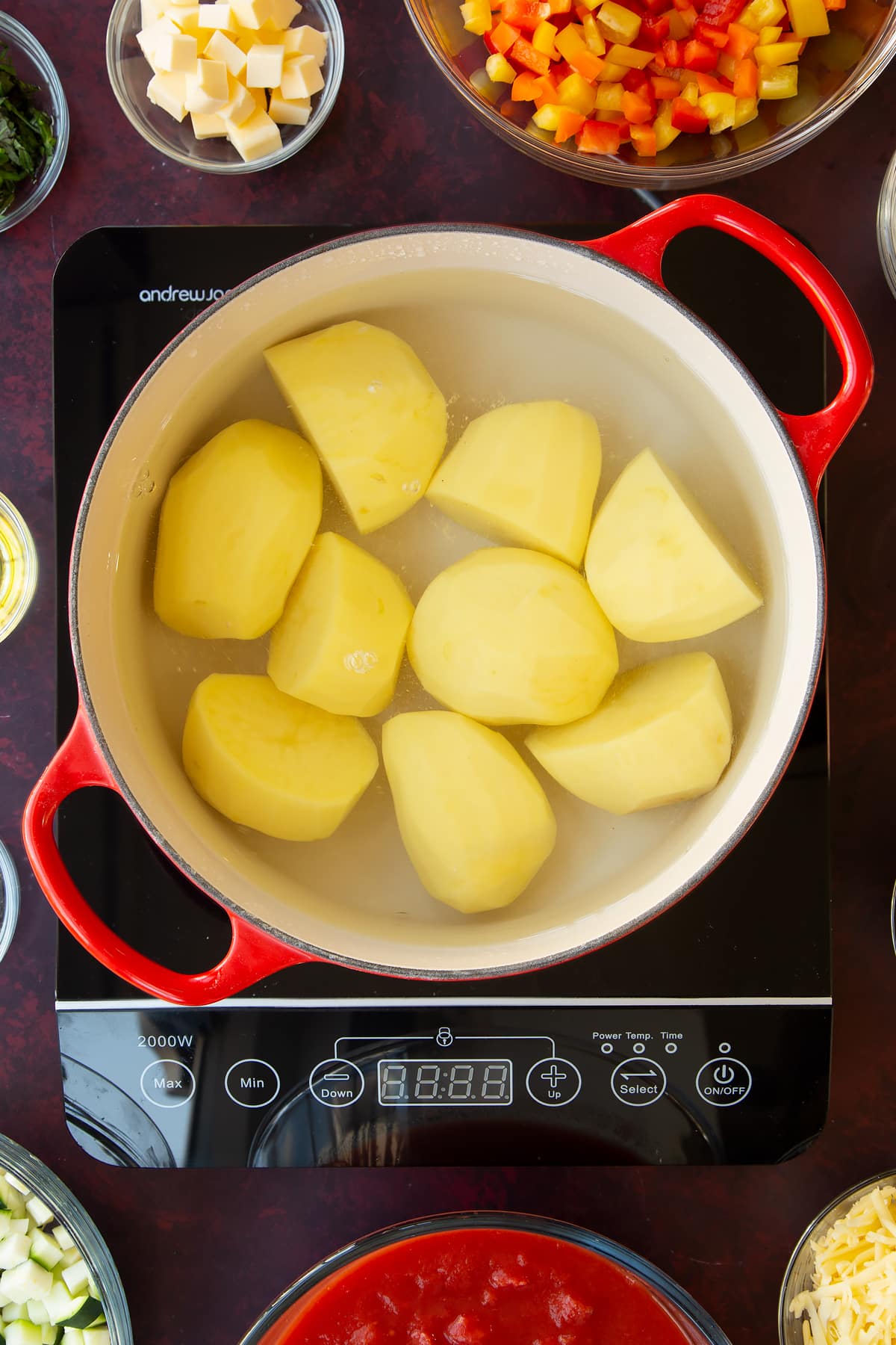 Overhead shot of a red pan with potatoes and boiling water.