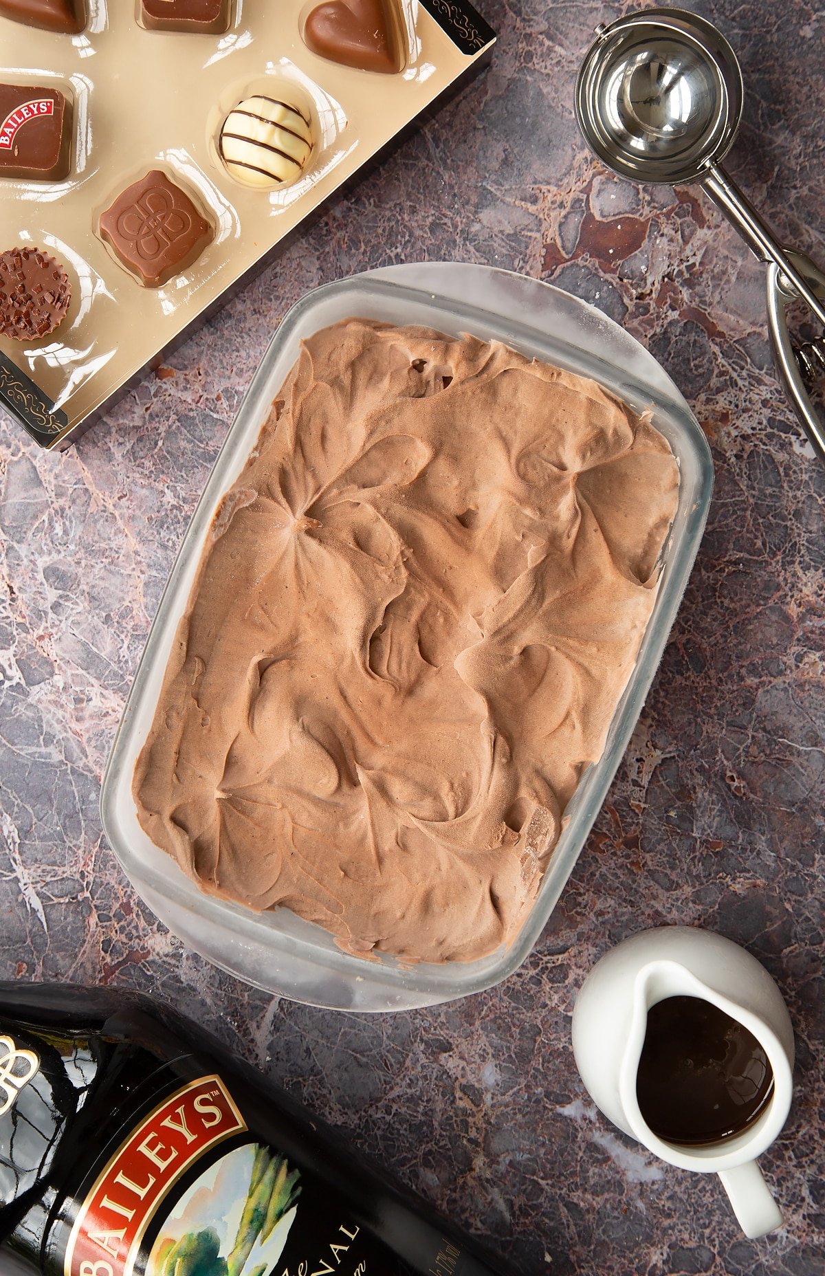 bailey ice cream mixture in a frozen pyrex dish with baileys chocolates at the side.