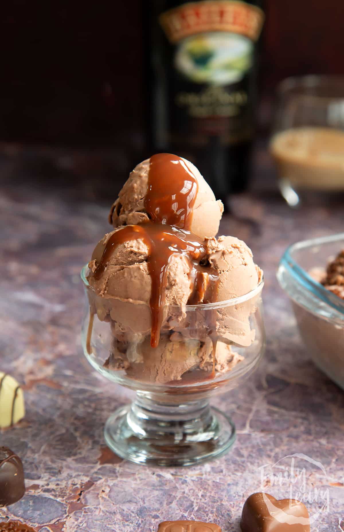 baileys ice cream in scoops in a glass dsessert bowl topped with choclate sauce