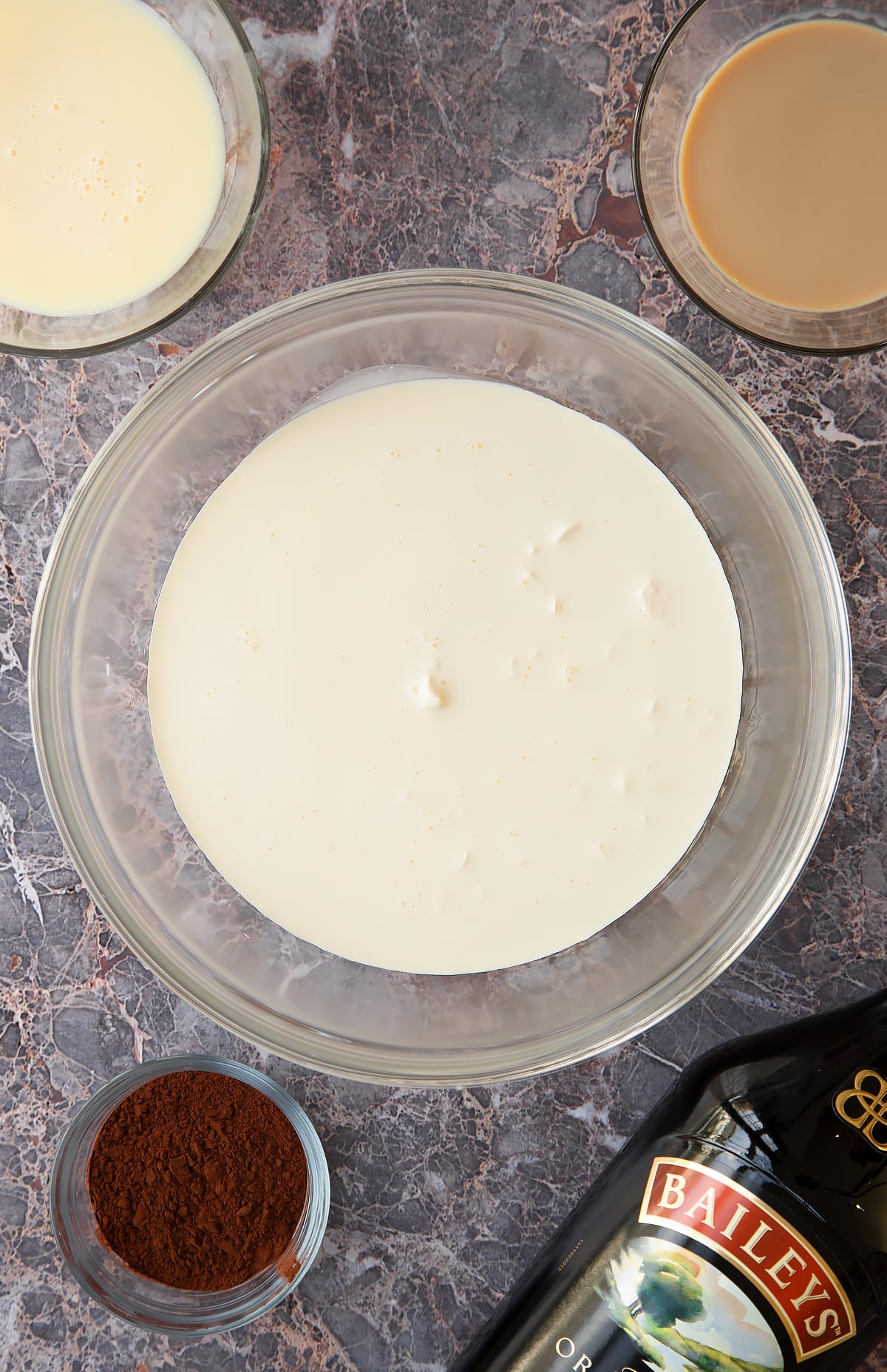 cream in a large mixing bowl with milk and baileys at the side.