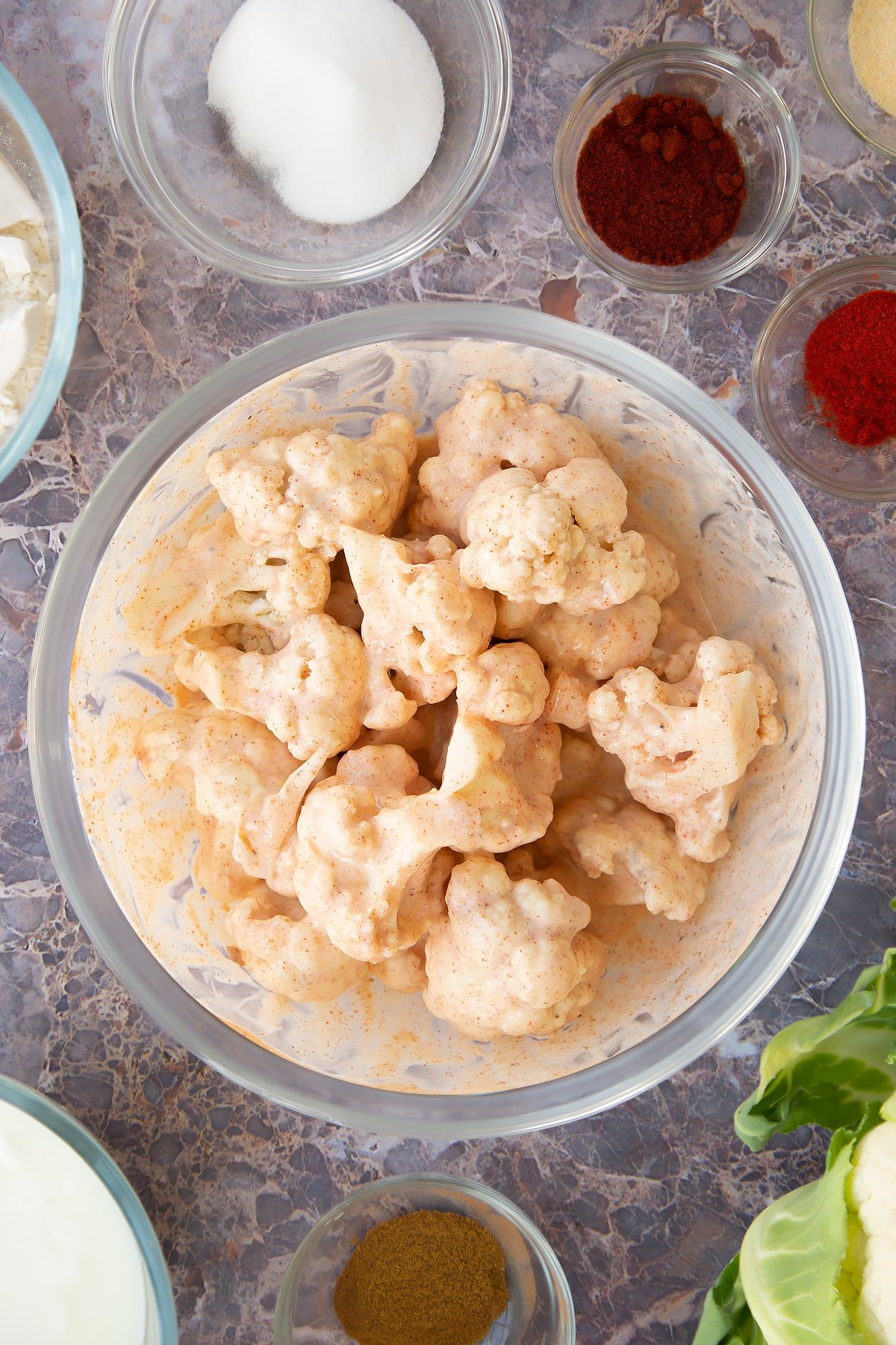 buttermilk coated cauliflower pieces in a large clear bowl.