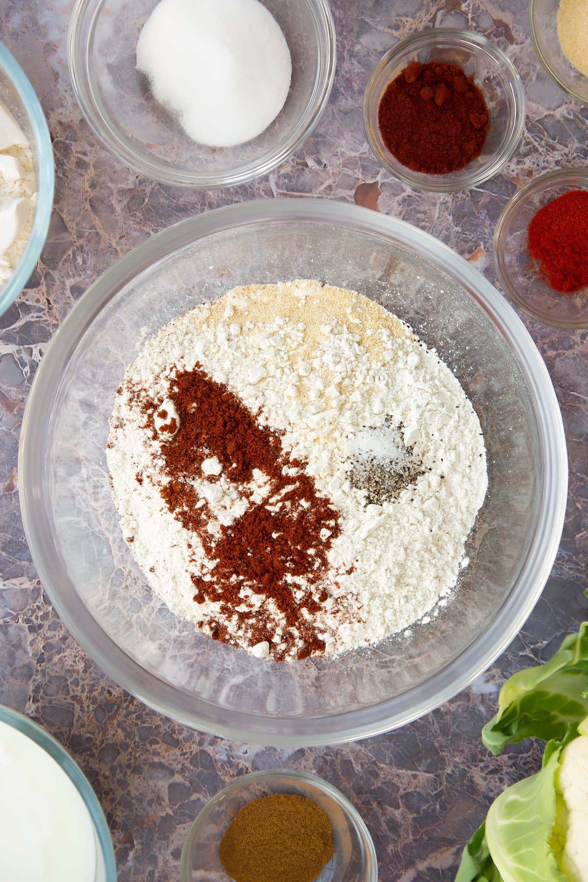 a large clear bowl with flour, cayenne and garlic in.