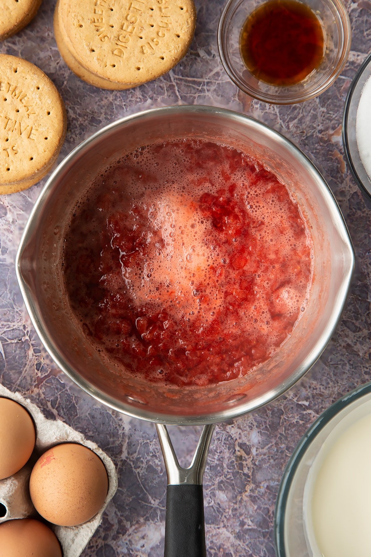 broken down strawberries in a pan with the sugar and lemon juice.