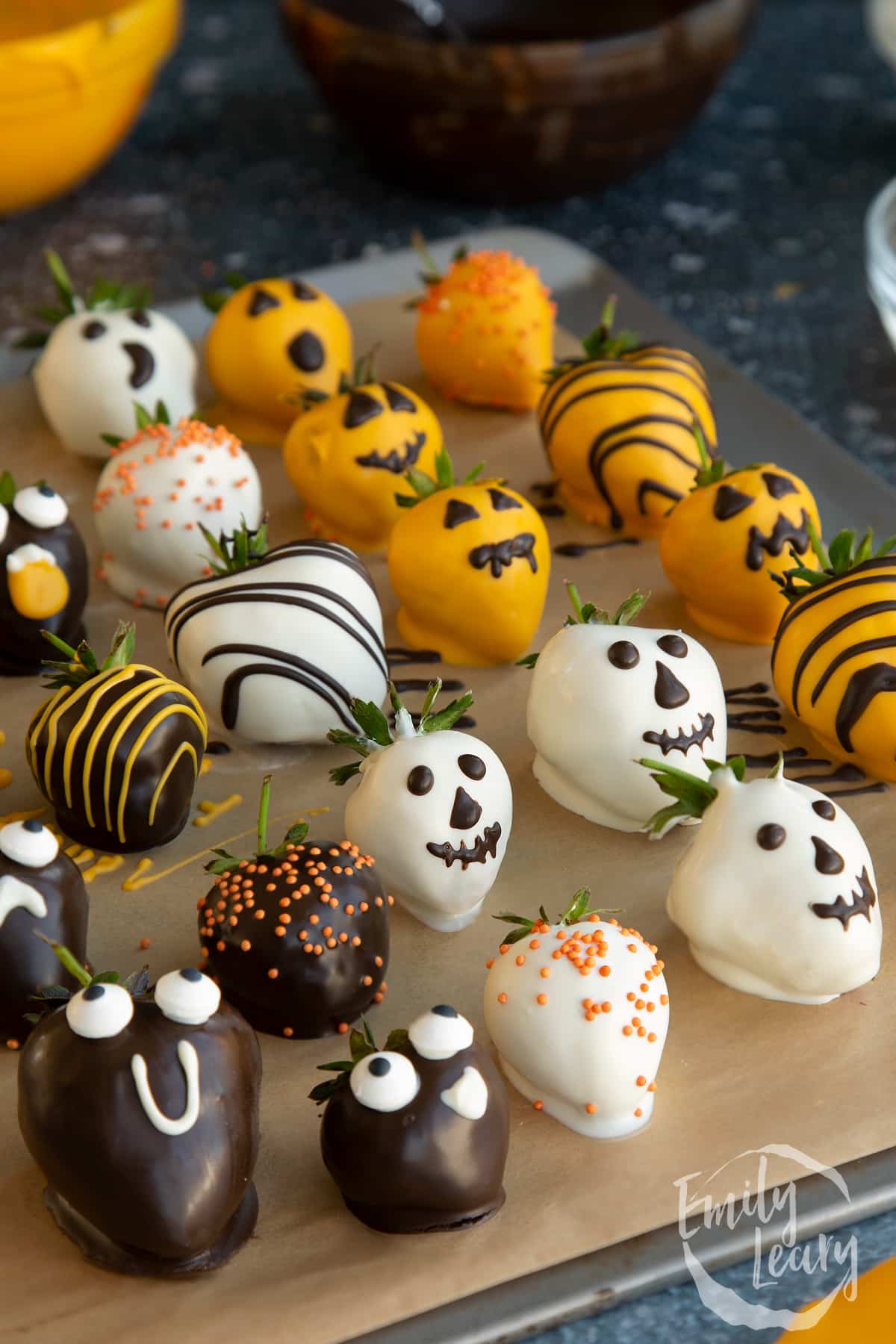 Side on shot of the decorated halloween chocolate covered strawberries on a baking sheet.