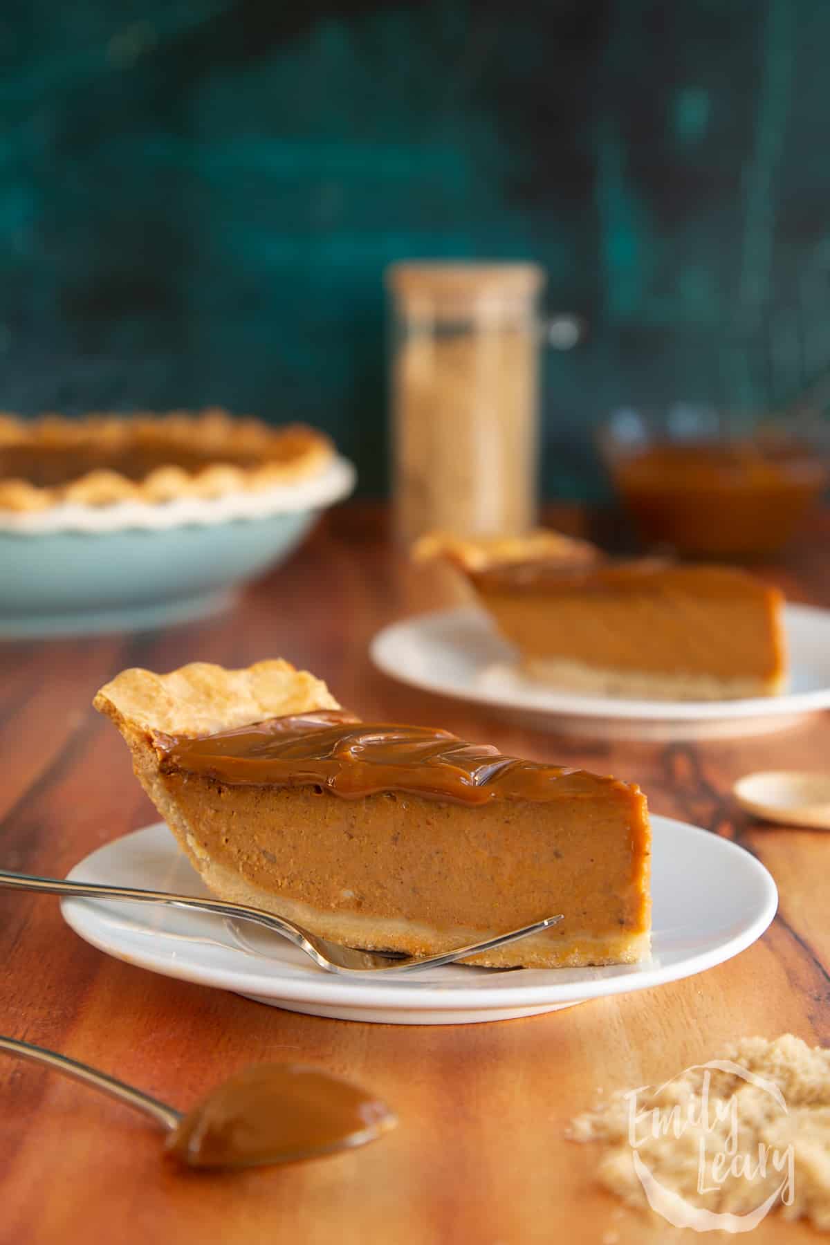 Sliced caramel pumpkin pie served on a white plate with a fork on the side.