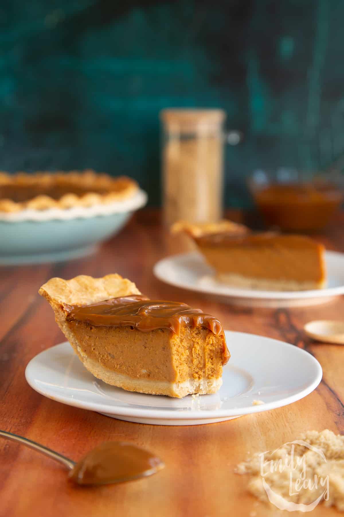 Sliced caramel pumpkin pie served on a white plate with a bite taken out of it.