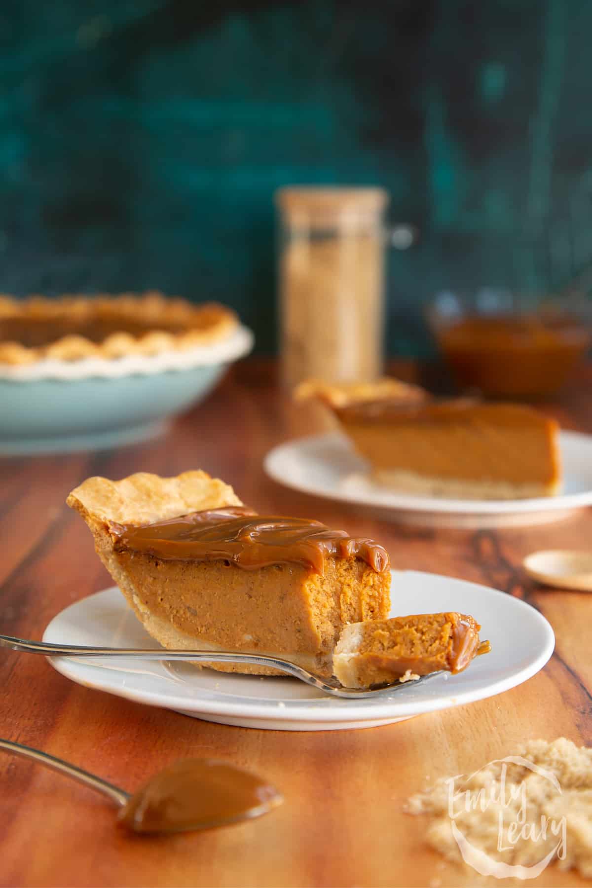 Sliced caramel pumpkin pie served on a white plate with a fork cutting into it.