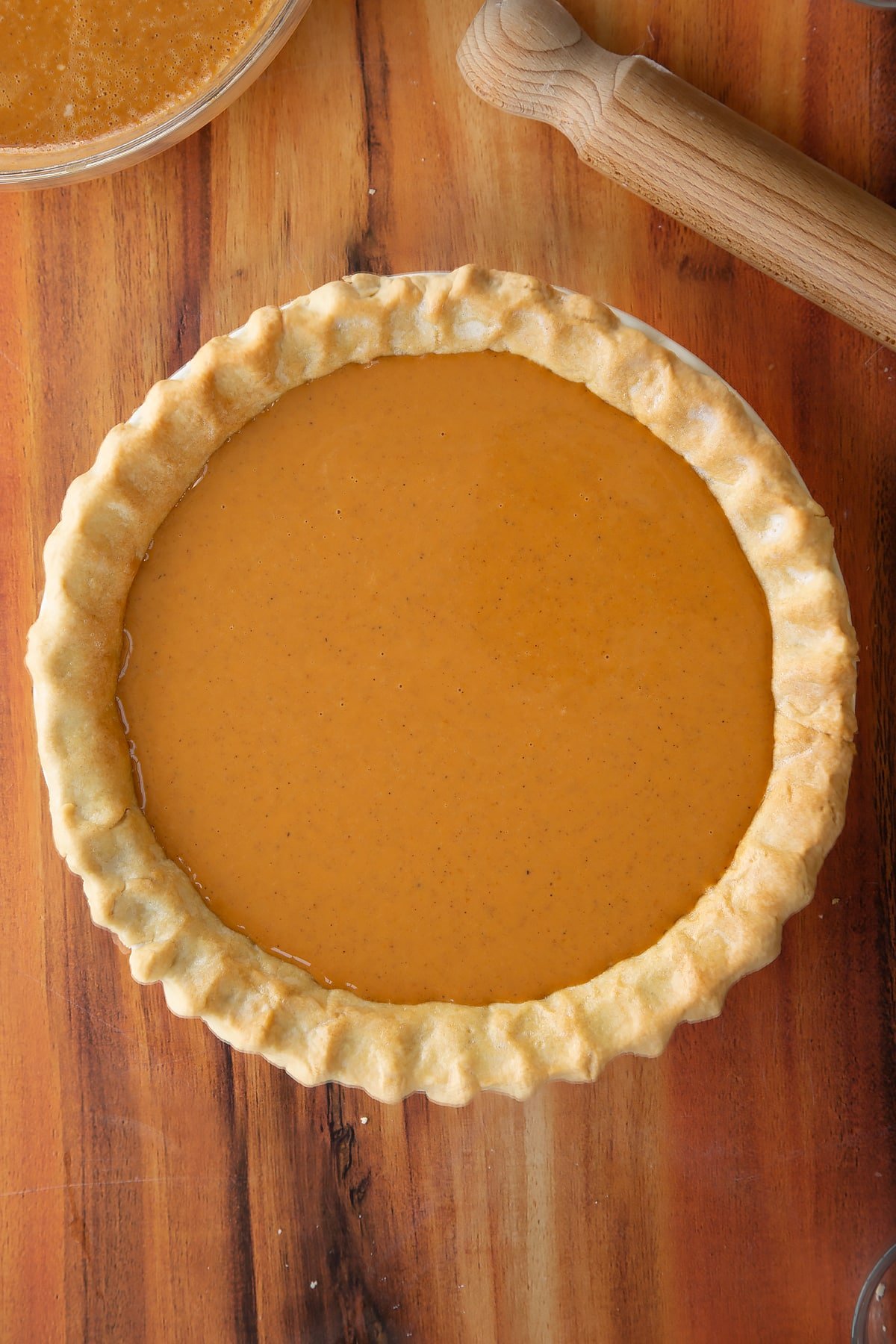 Adding the caramel pumpkin pie filling to the pie dough which has been pre-cooked.