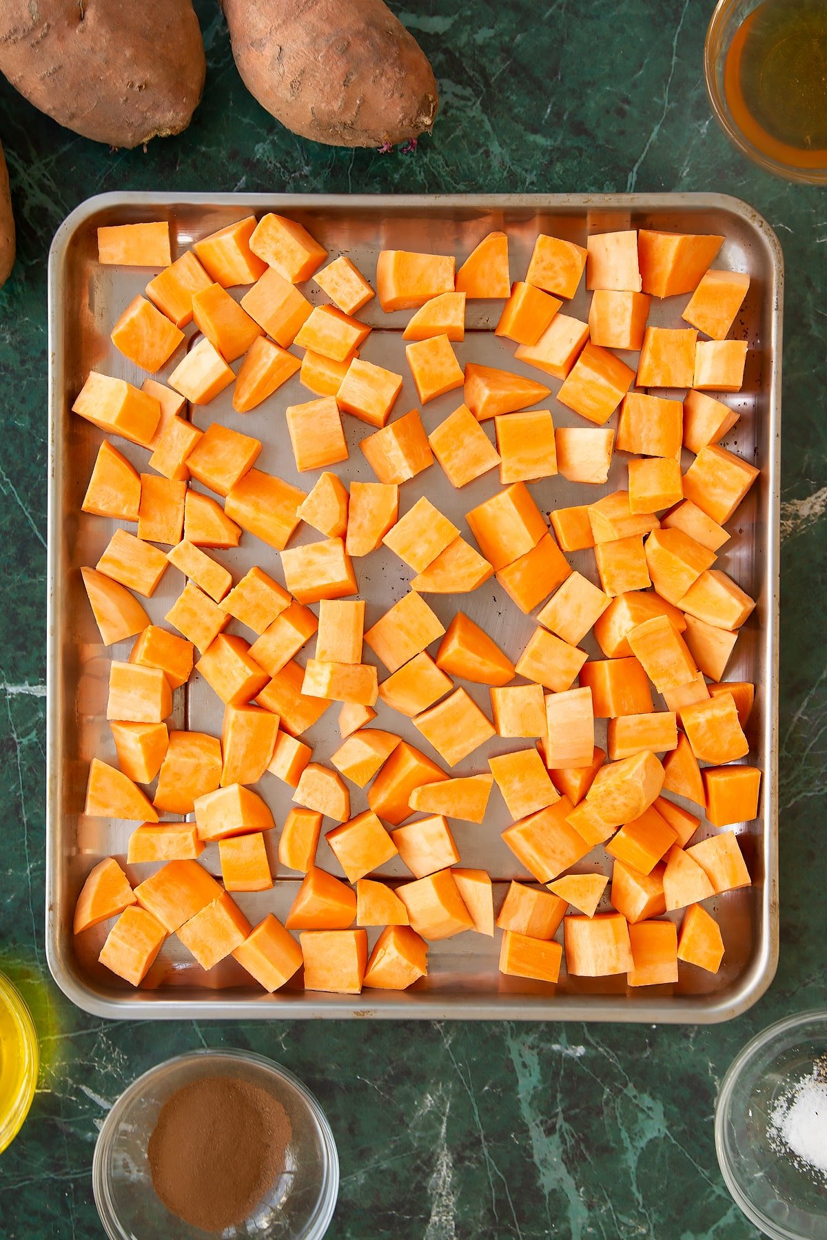 Chopped sweet potatoes on a large sheet pan.